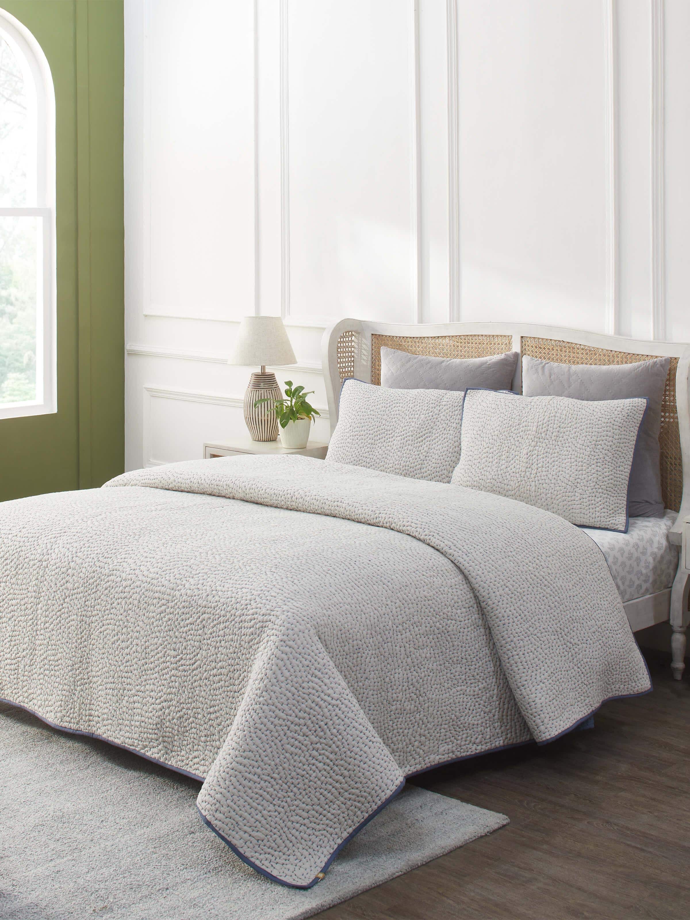 Lifestyle shot of a beige two-tone textured cotton razai embroidered double bedspread set, displayed in a bedroom setting.