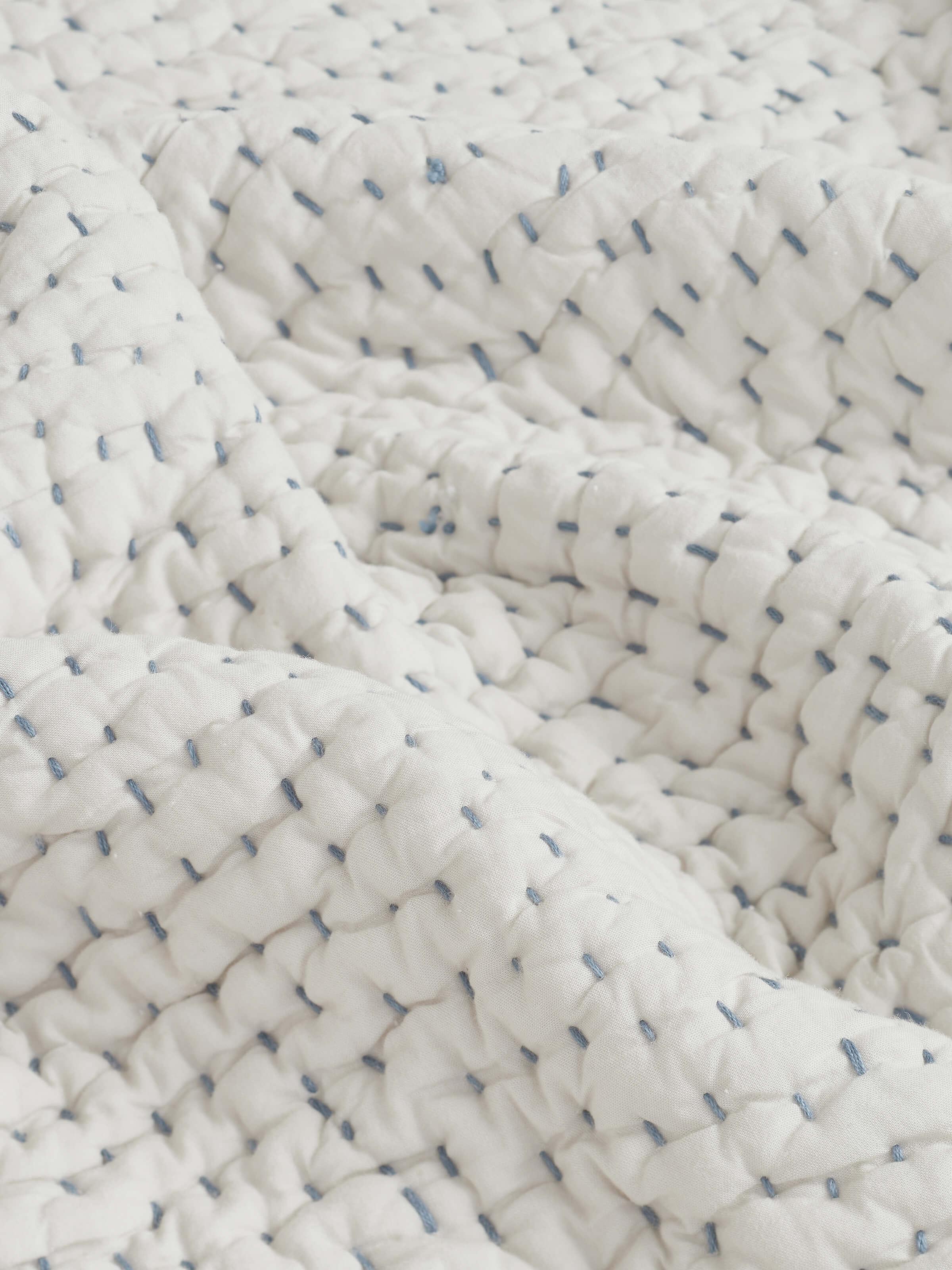 Detailed image of the edges and embroidery on the beige double bedspread, emphasizing the craftsmanship.