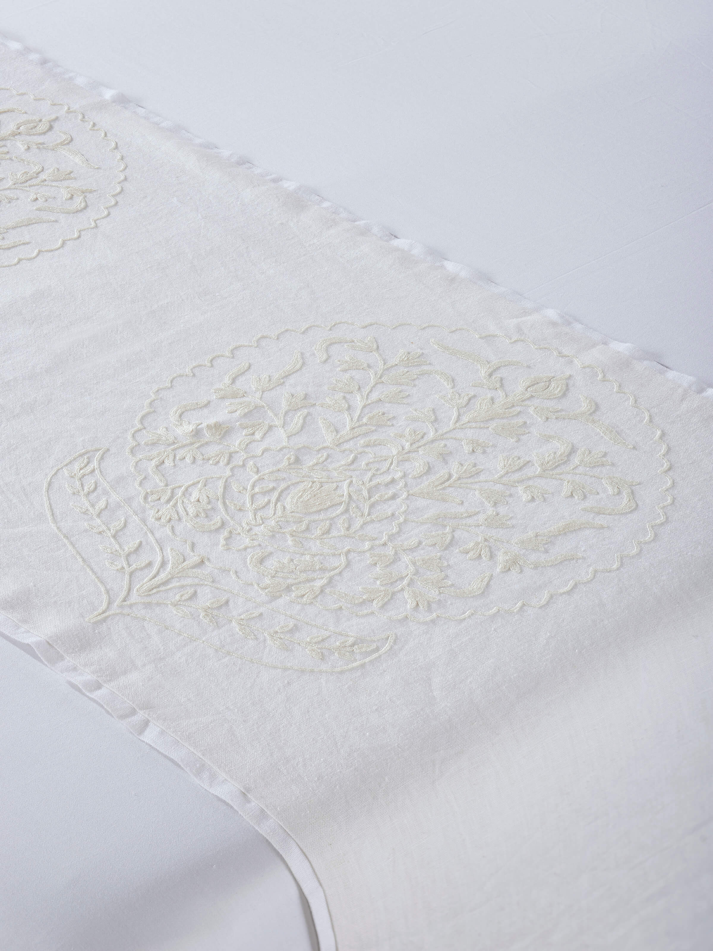 Side lifestyle view highlighting hand-embroidered buta details on linen bed runner.