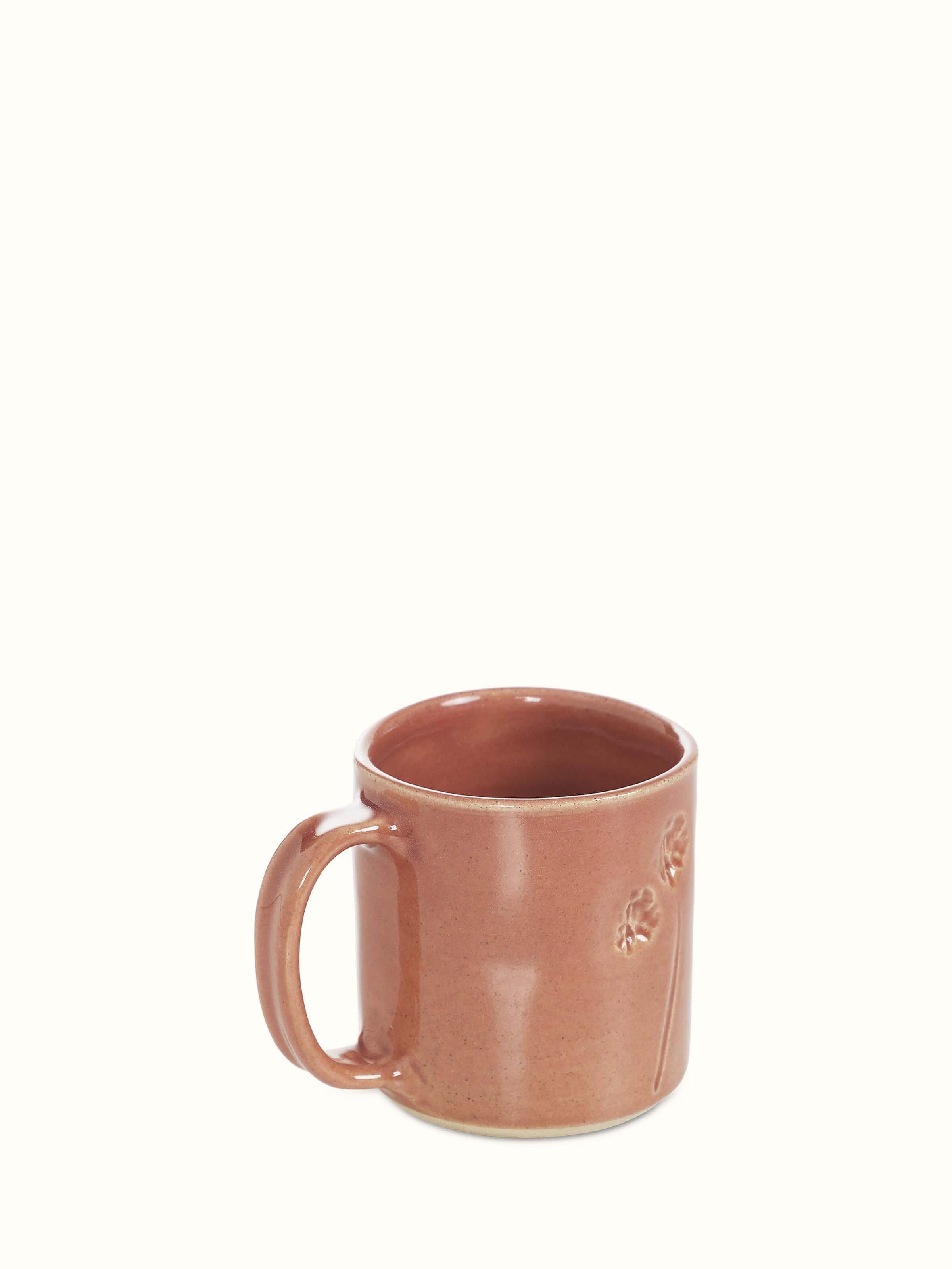 Angled view of Studio pottery ceramic coffee mug in pink emphasizing its refined shape and handcrafted quality.