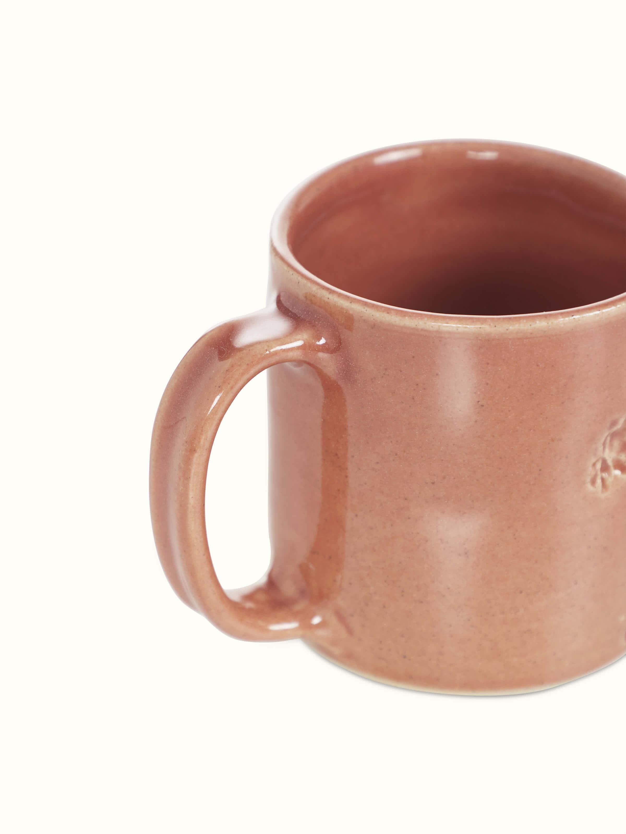Close-up view of Studio pottery ceramic coffee mug in pink focusing on the texture and color of the ceramic.