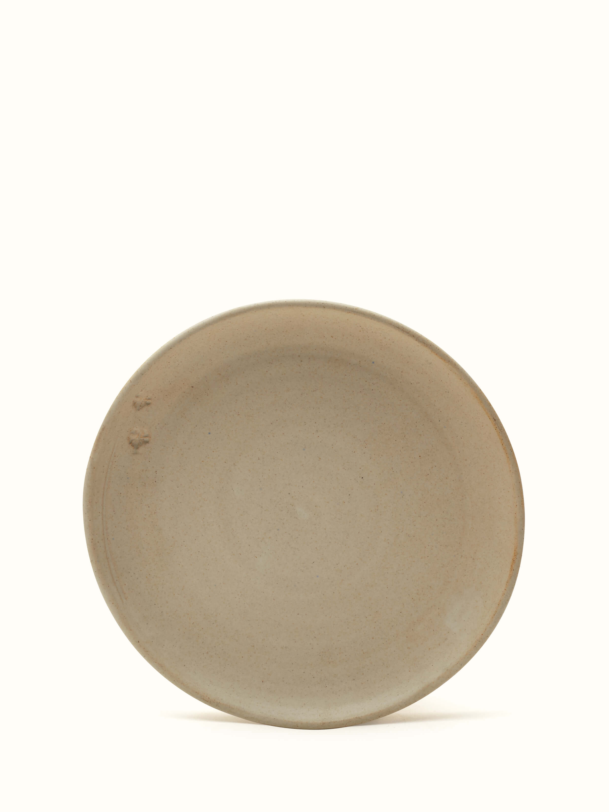Angle view of Studio Pottery Ceramic Dinner Plate Beige showcasing the shape and ceramic finish.