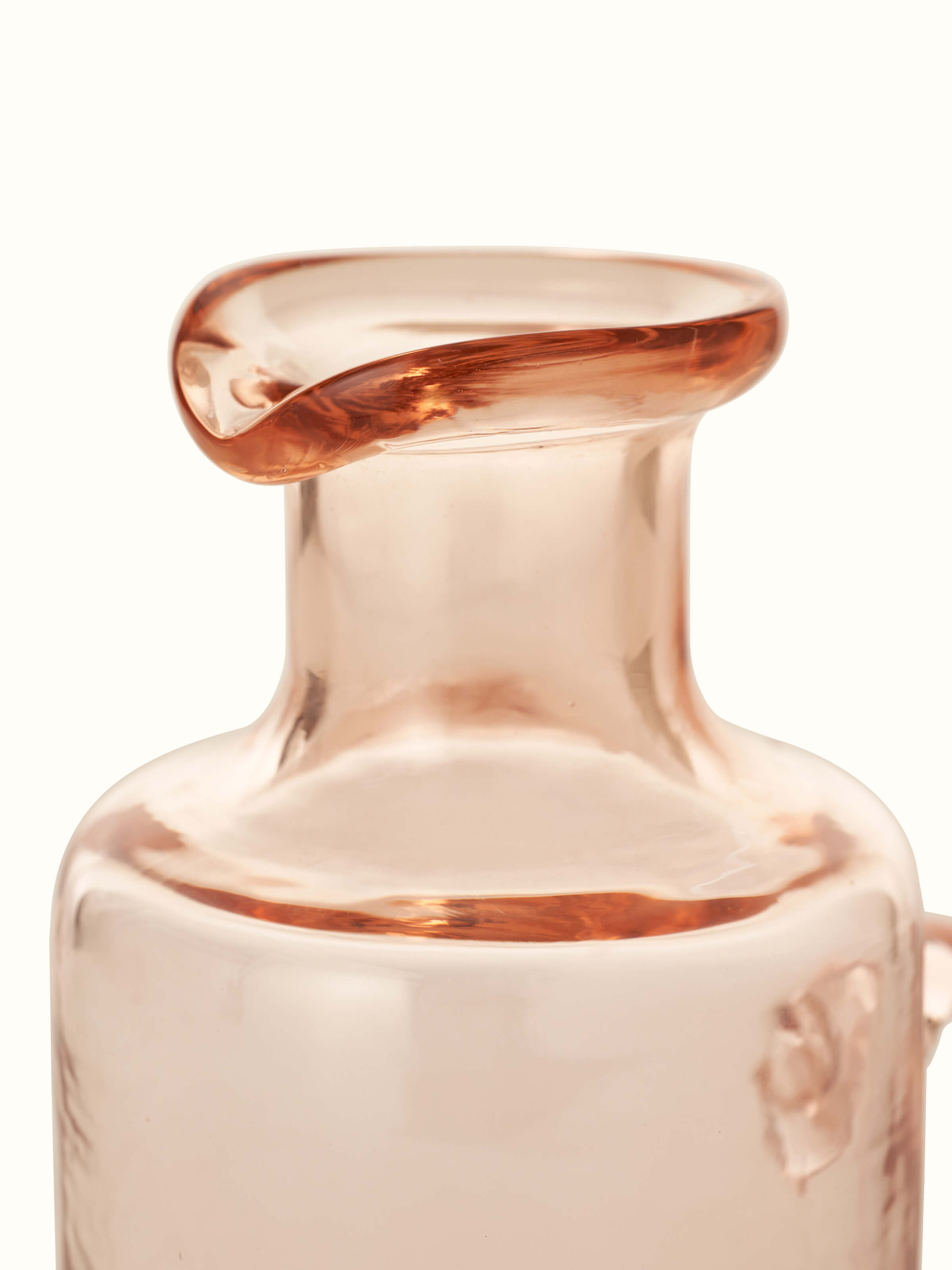 Angled view of Firozabadi glass pitcher in pink, showcasing its graceful curves.