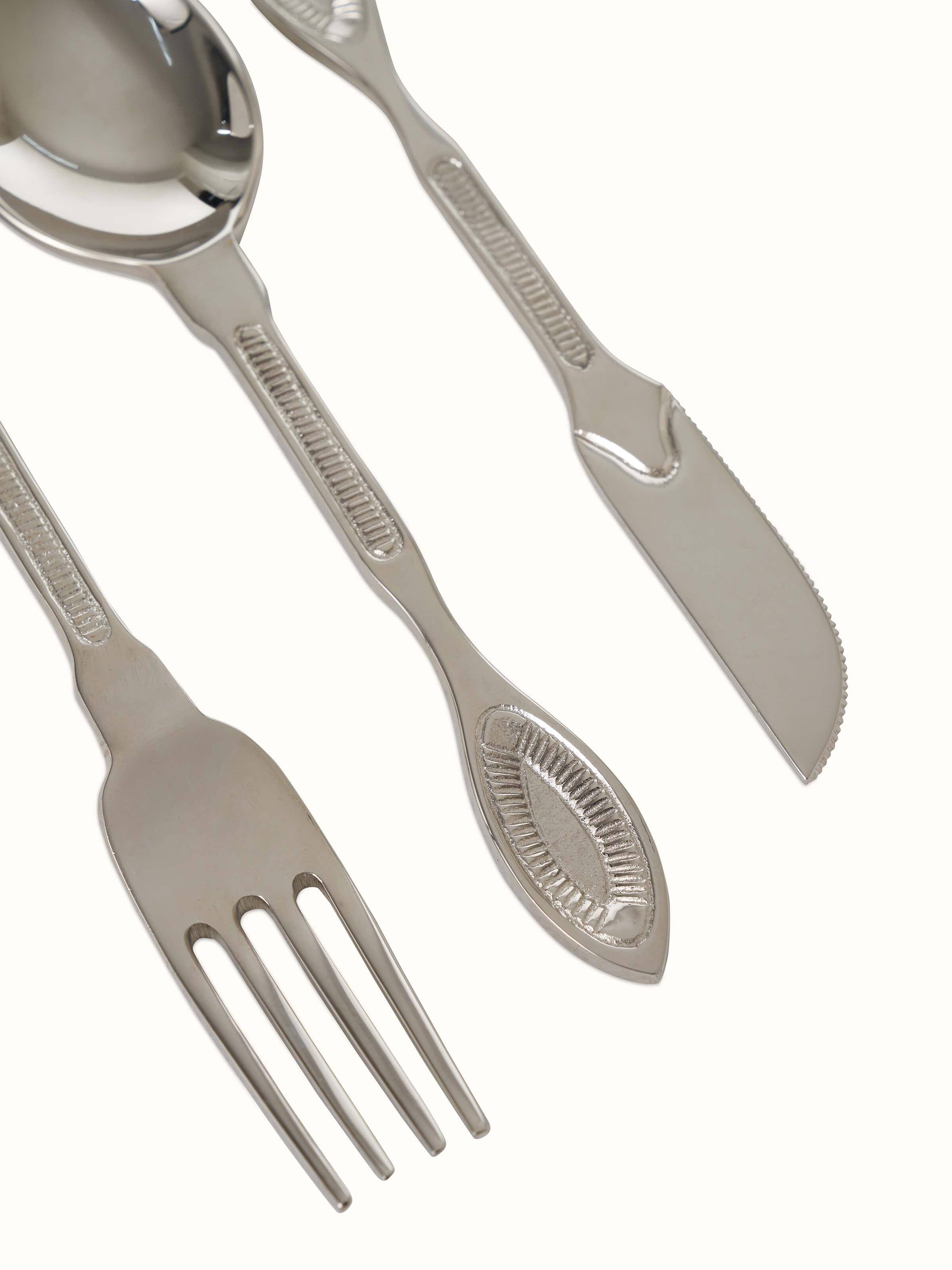 Close-up of Nakkashi brass cutlery set highlighting ornate patterns