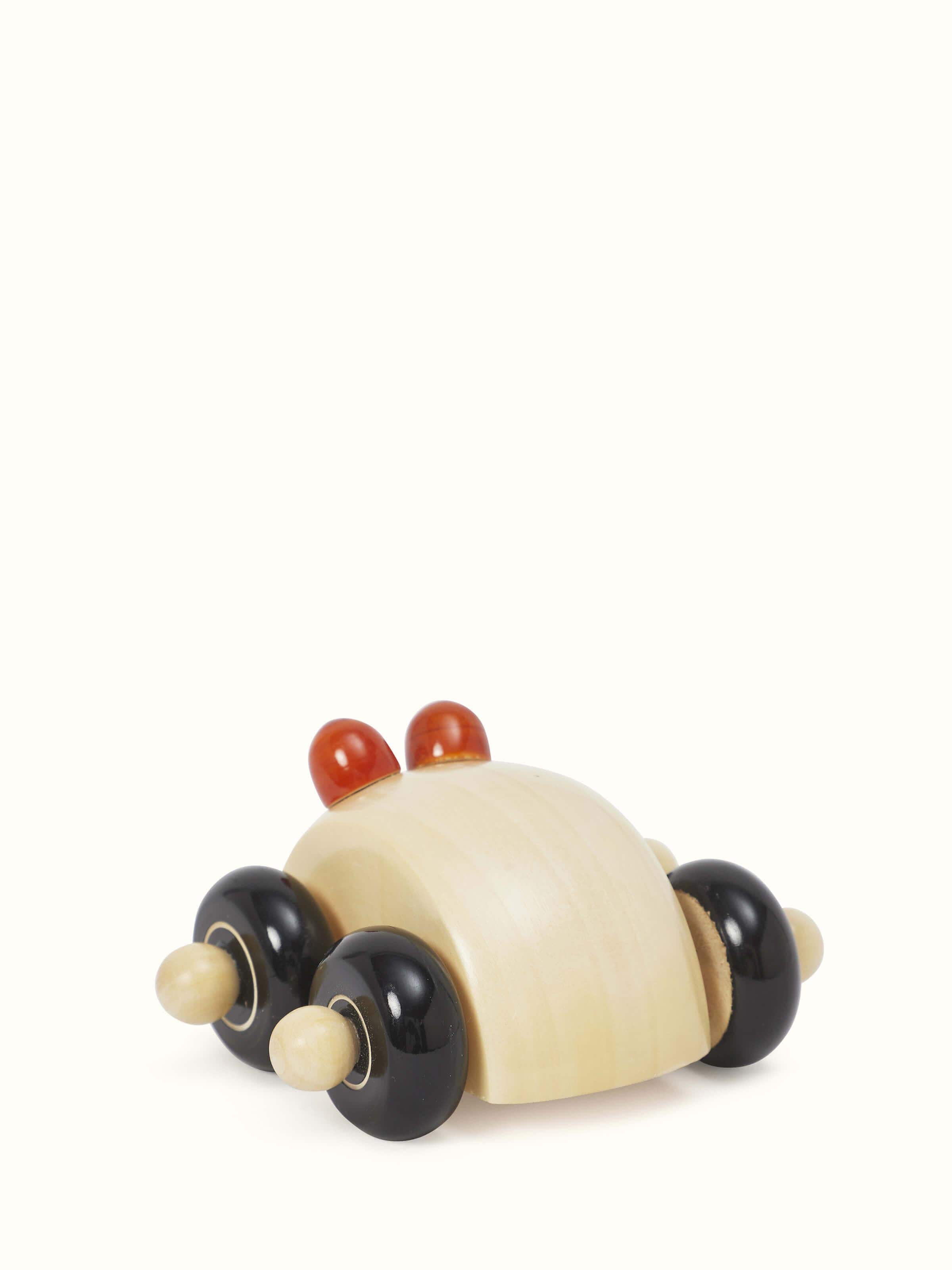 Side view of Channapatna ivory wood round car toy in off-white color highlighting the round shape and carved wood details.