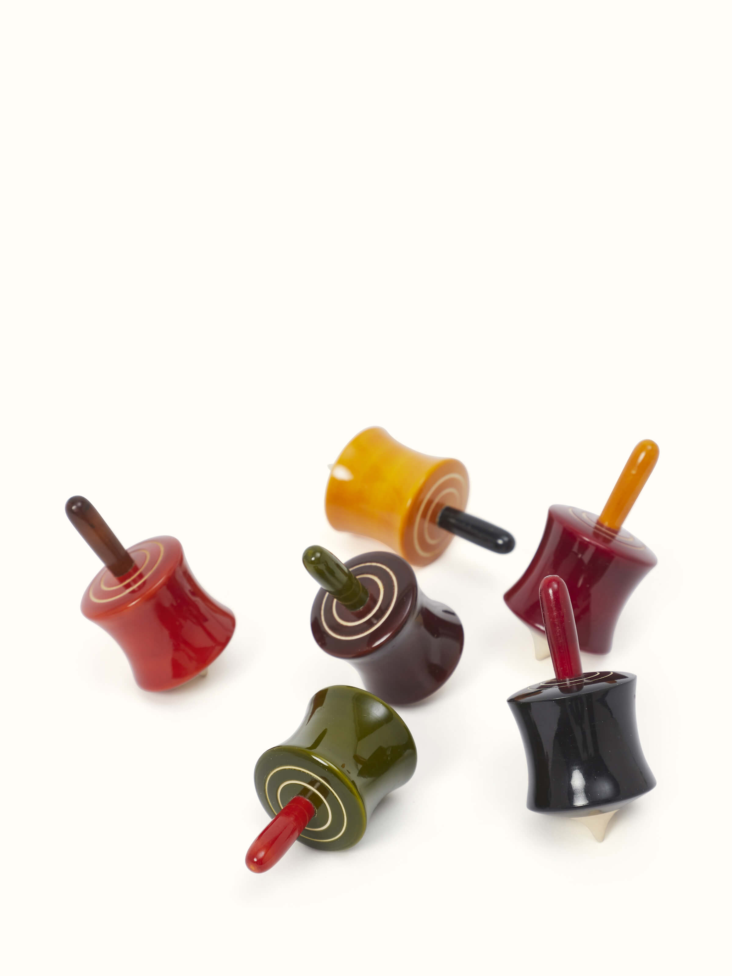 Close-up view of Channapatna ivory wood cylinder spinning toys, highlighting the intricate design.