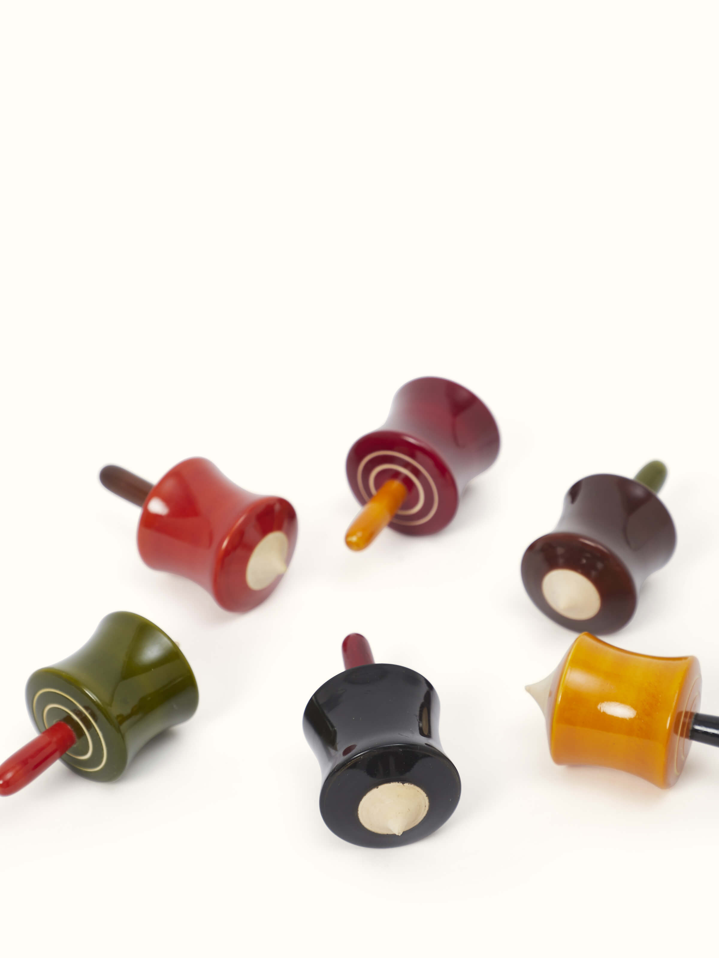Another angle of Channapatna ivory wood cylinder spinning toys, showcasing their detailed features.