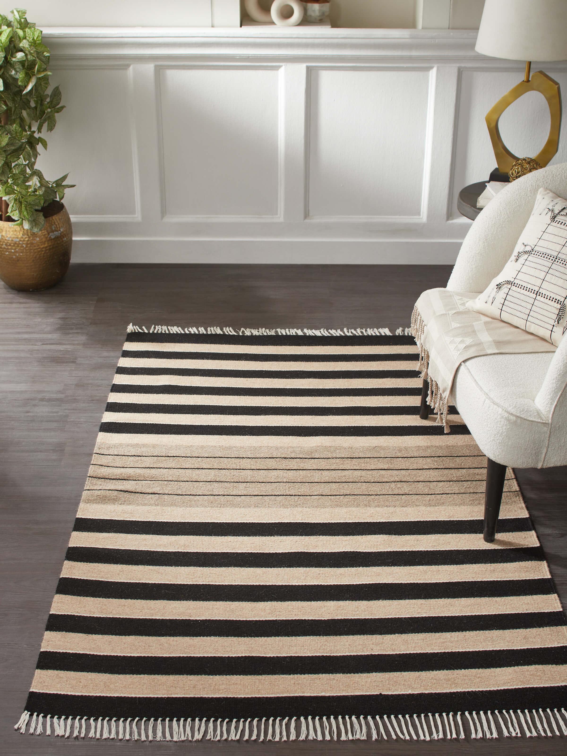 Lifestyle view of black-beige striped Jawaja wool handloom dhurrie, 4x6 ft, adding contrast to wooden flooring.