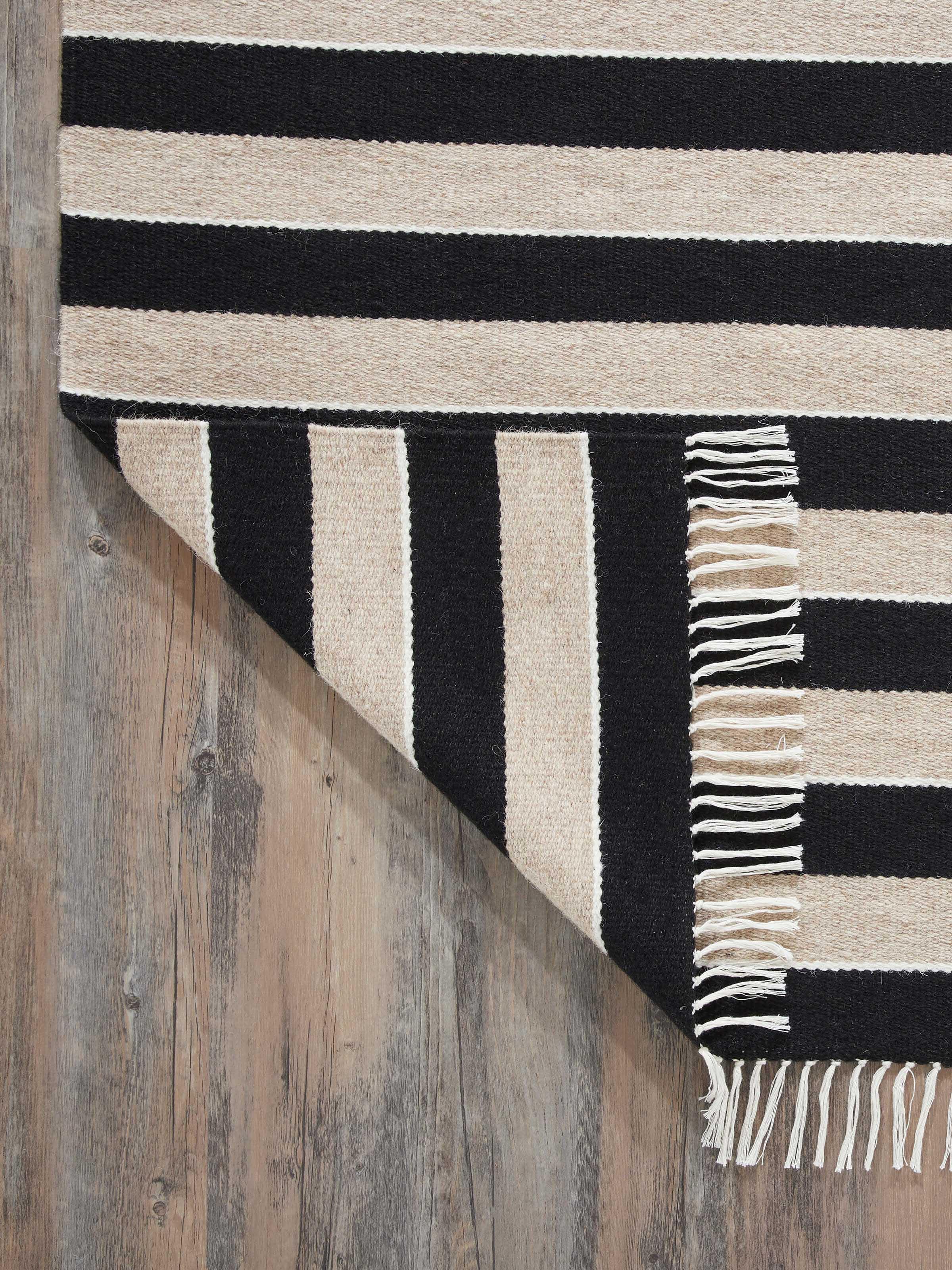 Angled view of Nomad Stripes Black Beige Jawaja Wool & Cotton Handloom Dhurrie (4x6 ft) with visible stripe pattern