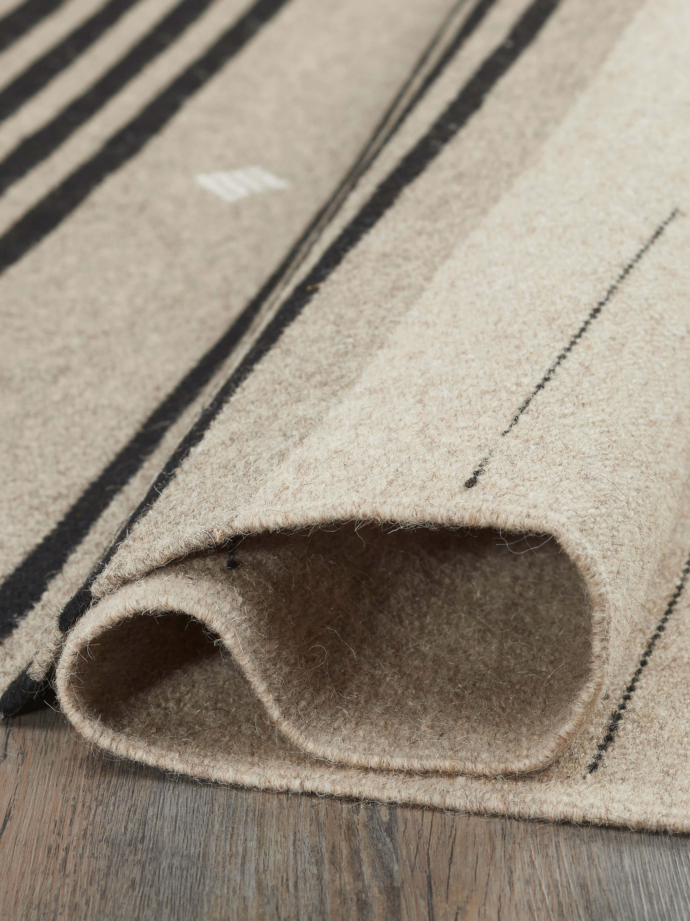 Nomad stripes beige black Jawaja wool & cotton handloom dhurrie (4x6 ft) folded to show the fabric and stripe pattern details.