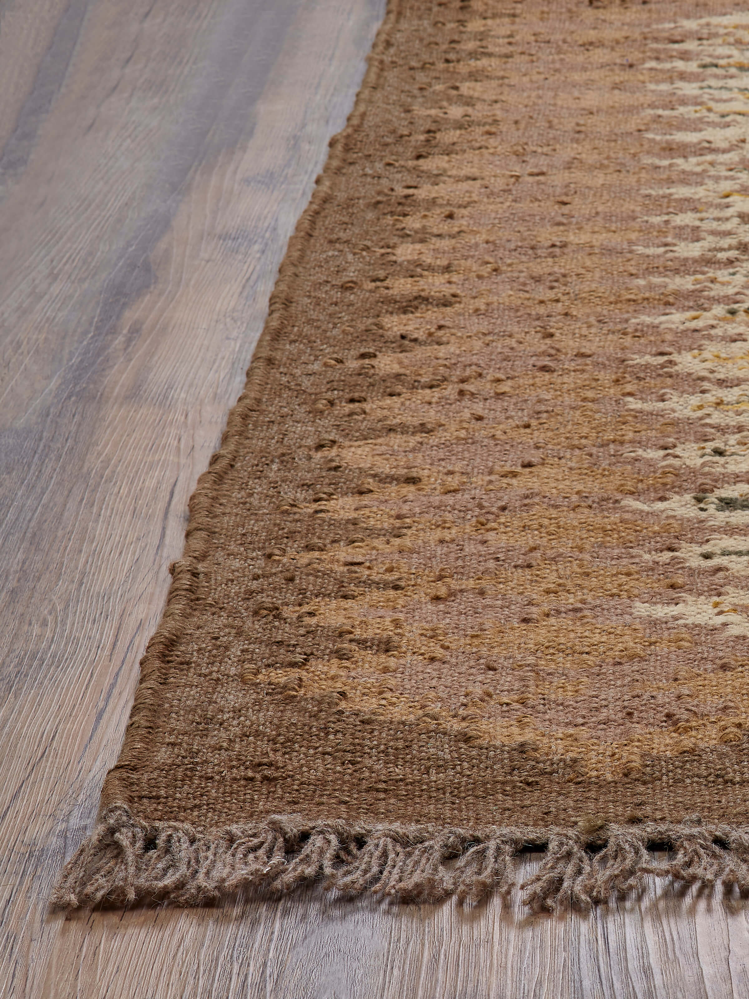 Angled view of a traditional kilim brown jute & wool panja dhurrie, highlighting the detailed patterns and earthy tones.