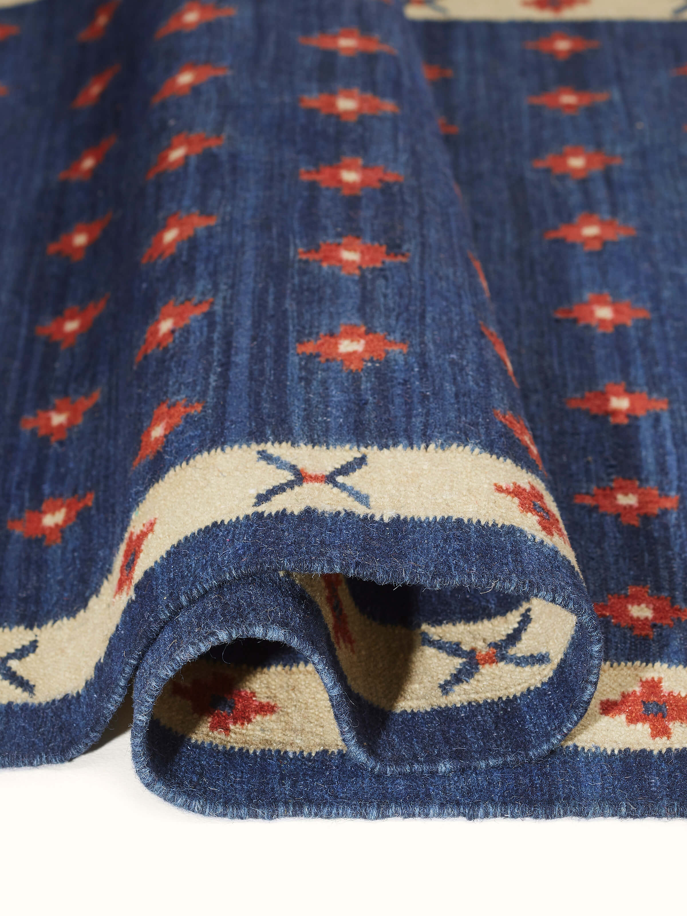 Close-up of dotted diamond blue rust salawas wool & cotton panja dhurrie highlighting the detailed pattern and craftsmanship