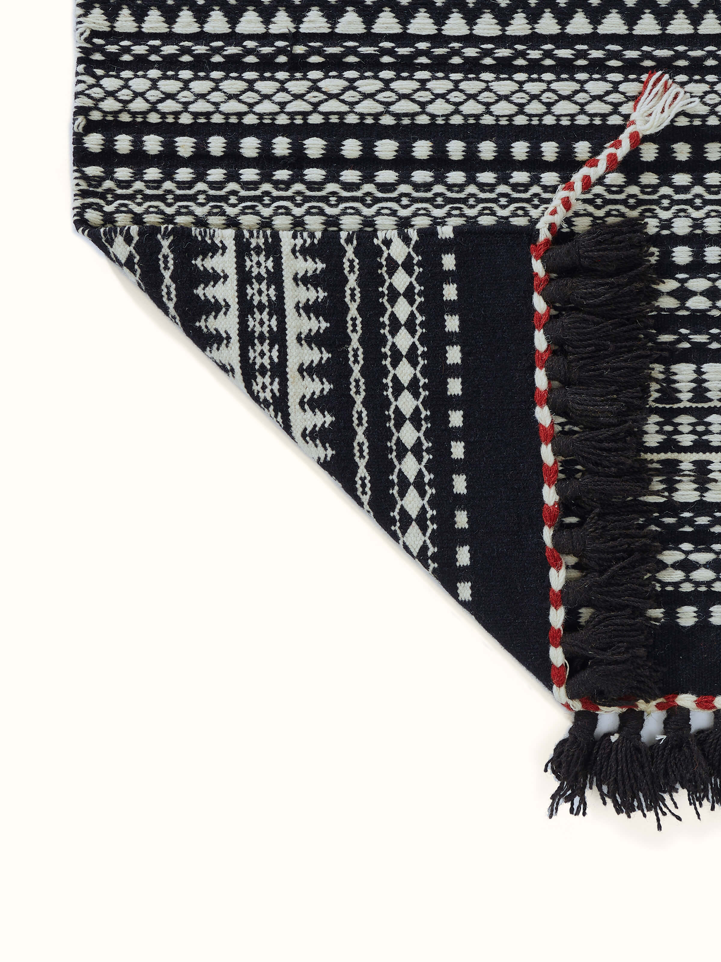 Side view of Sindhi textured ivory black salawas wool panja dhurrie, demonstrating its thickness and texture.