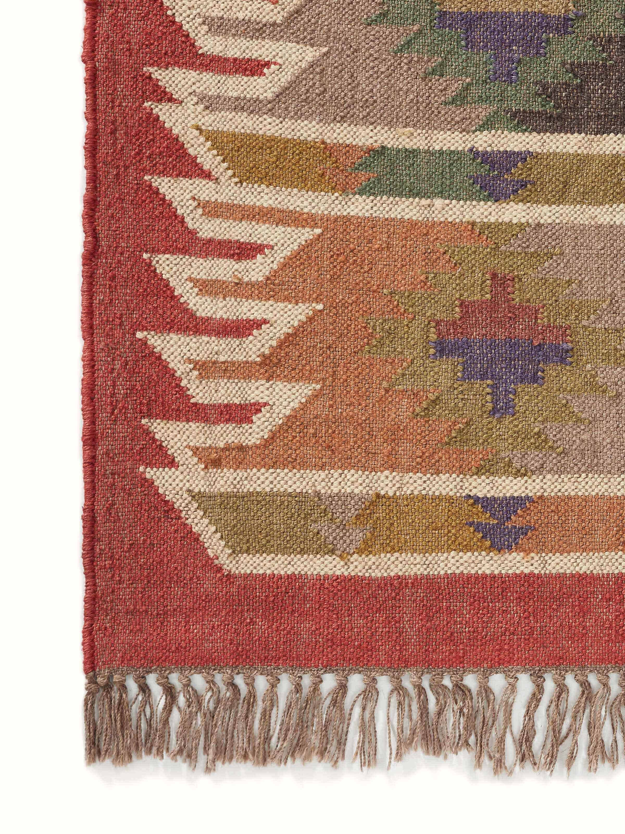 Traditional kilim rust green lawan jute & wool panja dhurrie shown folded, emphasizing its craftsmanship and color.