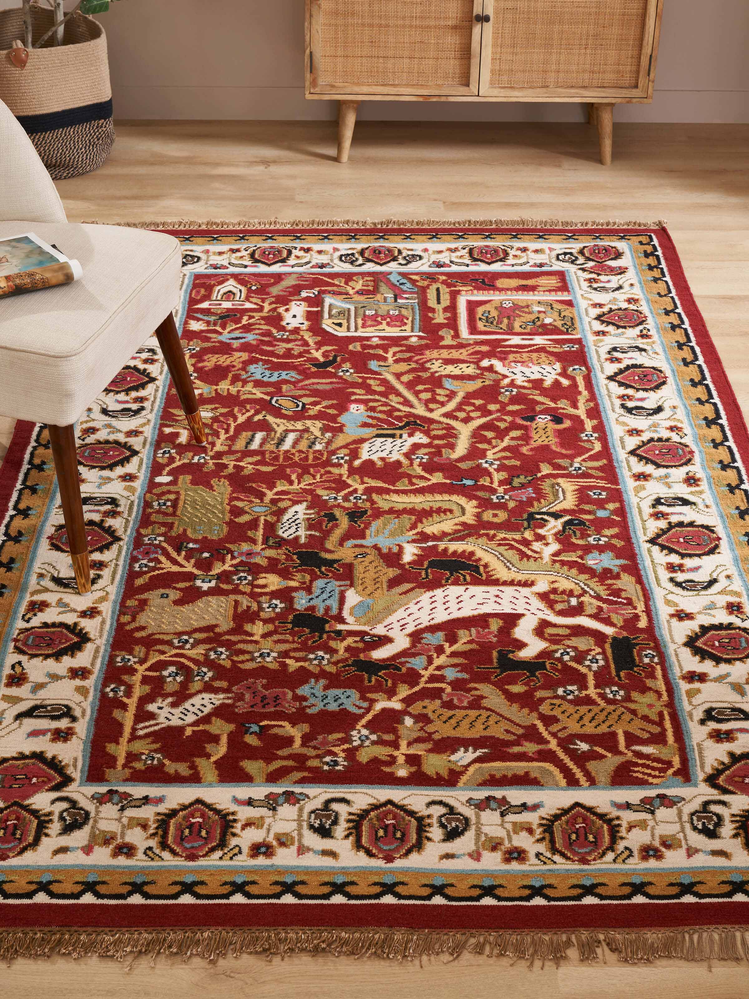 Close-up of the Village pictorial red wool & cotton panja dhurrie, highlighting the detailed patterns and textures