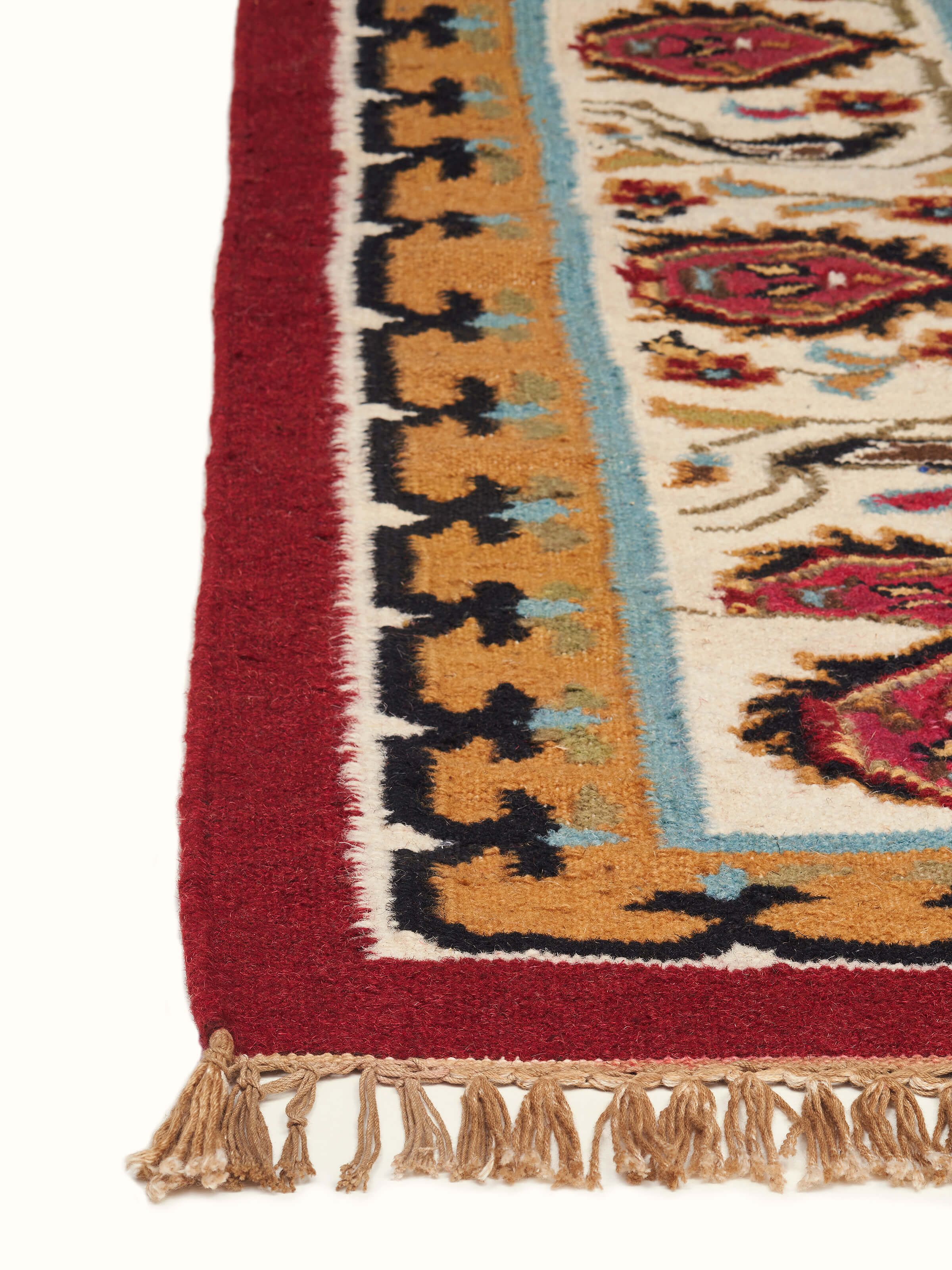 Village pictorial red wool & cotton panja dhurrie displayed in a room, illustrating its size and overall appearance