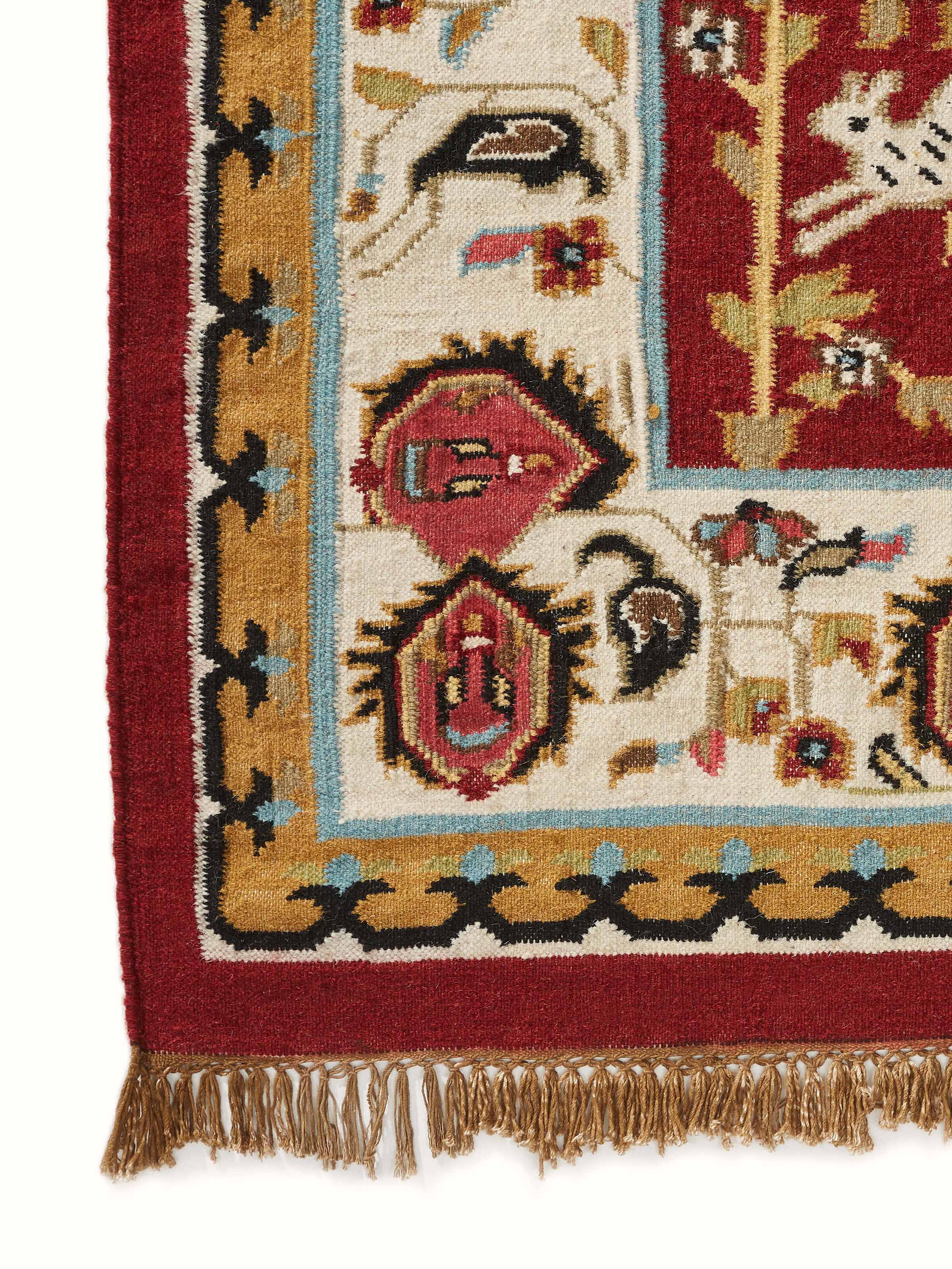 Detailed view of the Village pictorial red wool & cotton panja dhurrie’s intricate design and rich colors