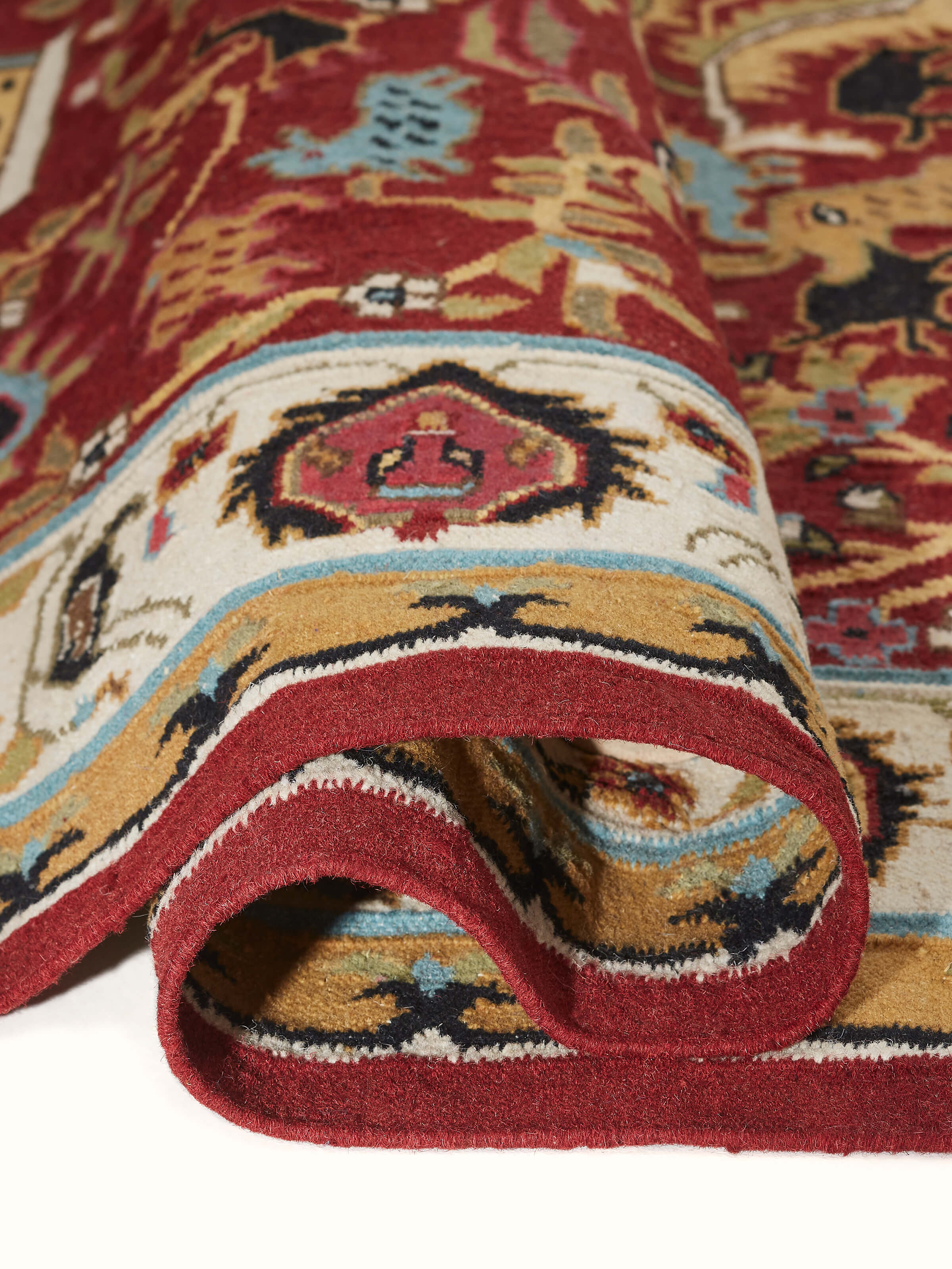 Folded Village pictorial red wool & cotton panja dhurrie, showing the thickness and texture of the fabric