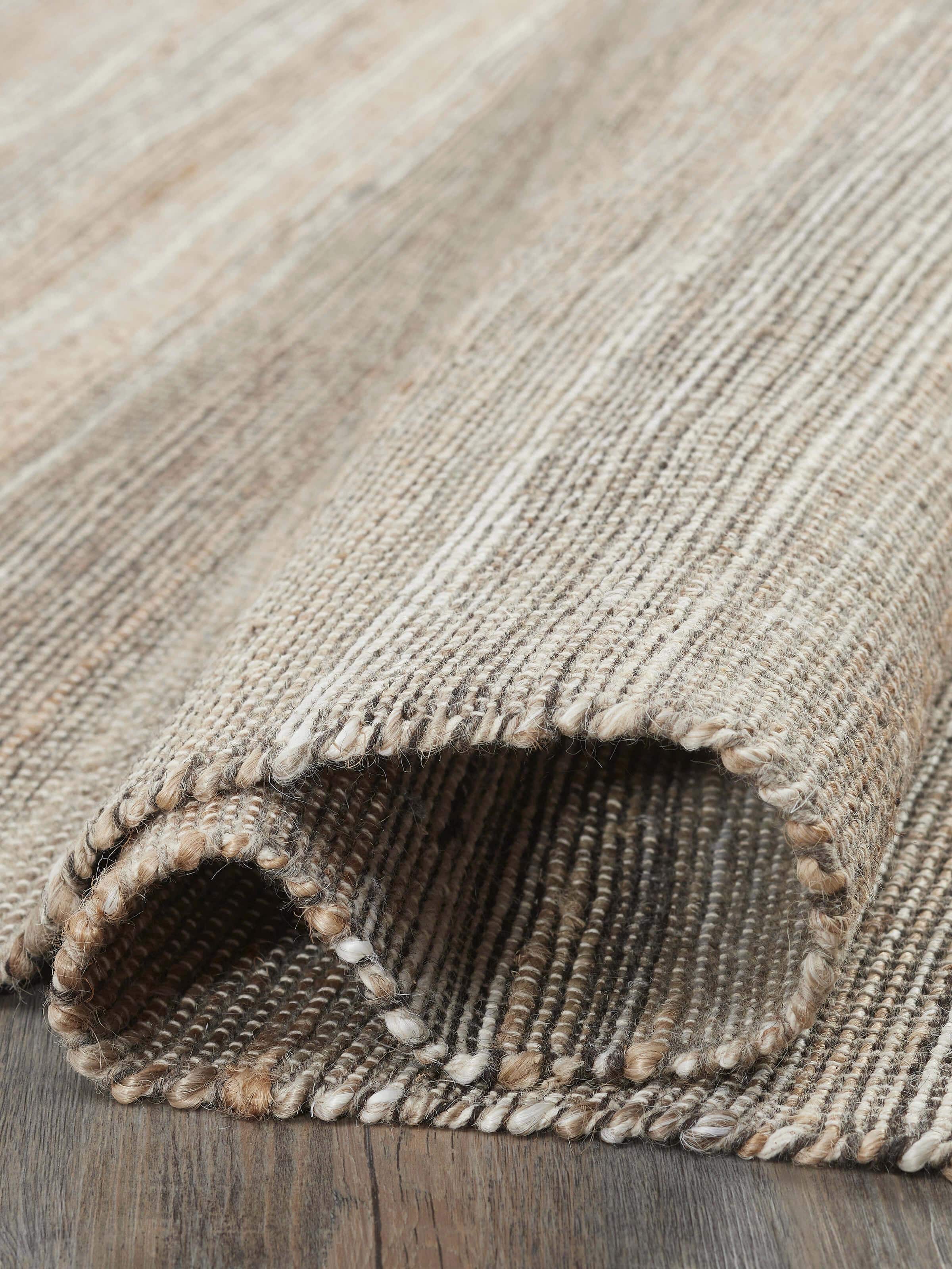 Side view of Textured Beige Black Lawan Jute & Cotton Rug, showing the edge and thickness of the rug.