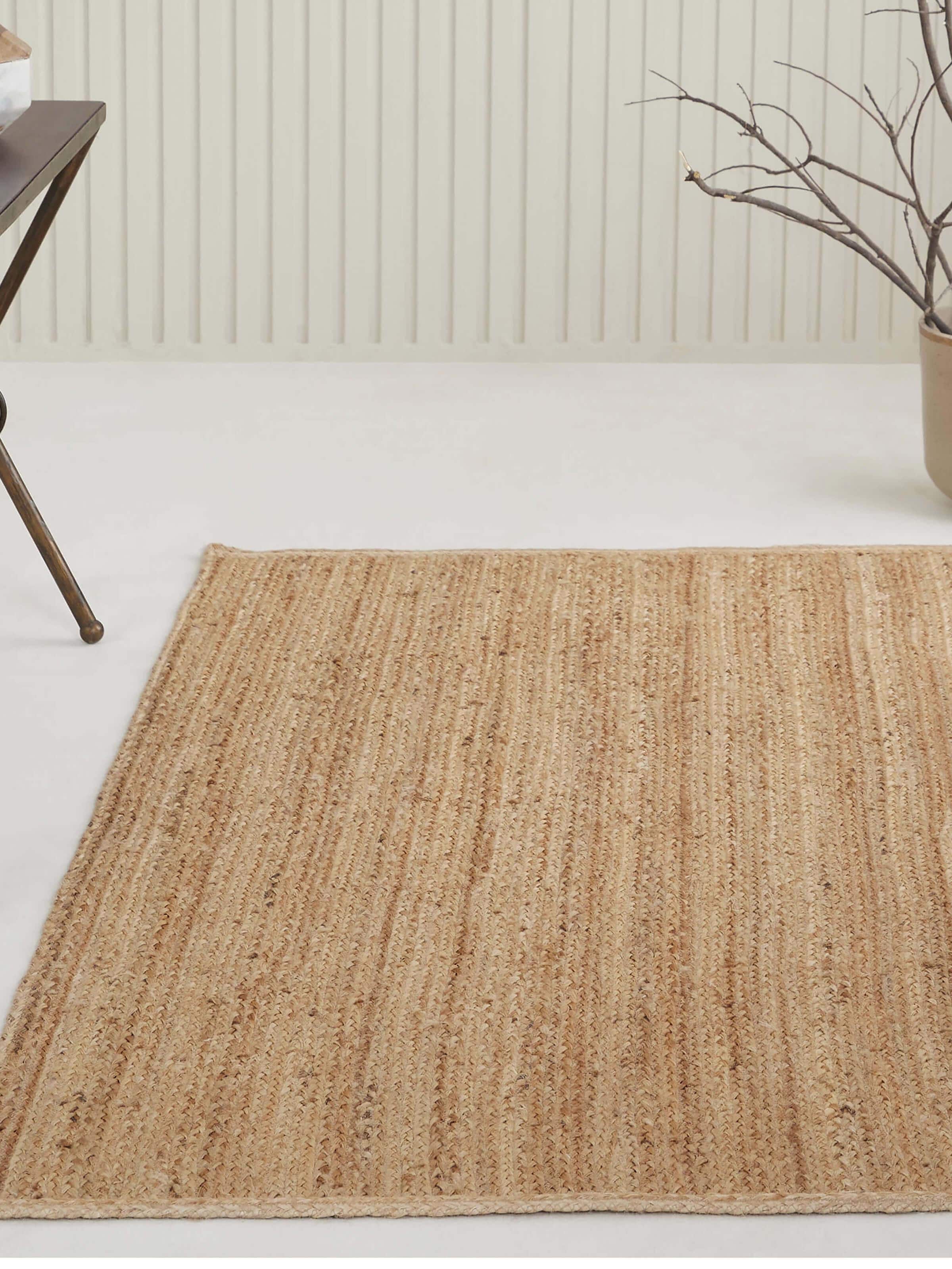 Living room view of beige jute rug with braided stripe texture in a natural fibre finish.