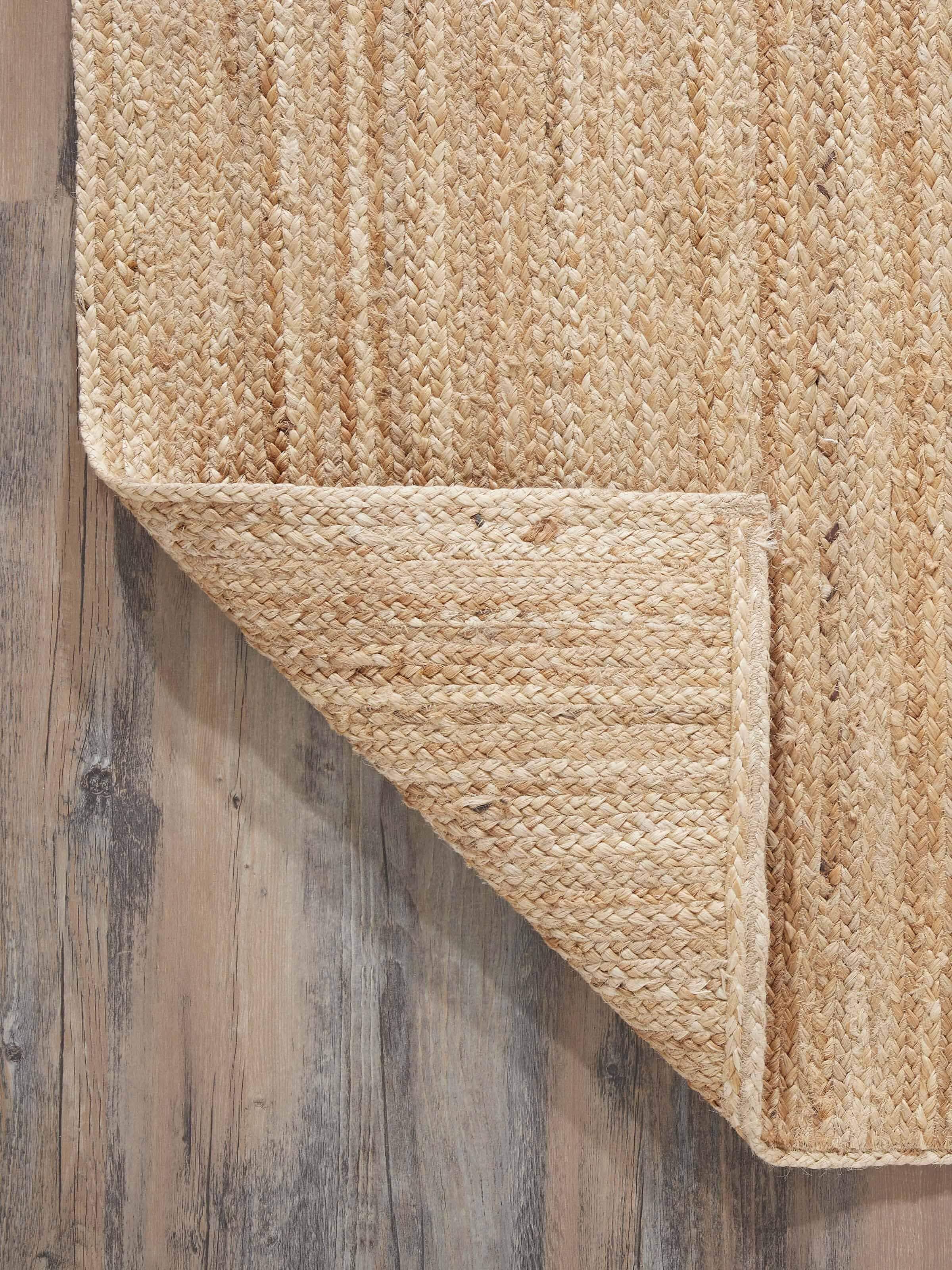 Full view of the braided stripe beige Lawan jute natural fibre rug, showcasing its placement and design in a room setting.