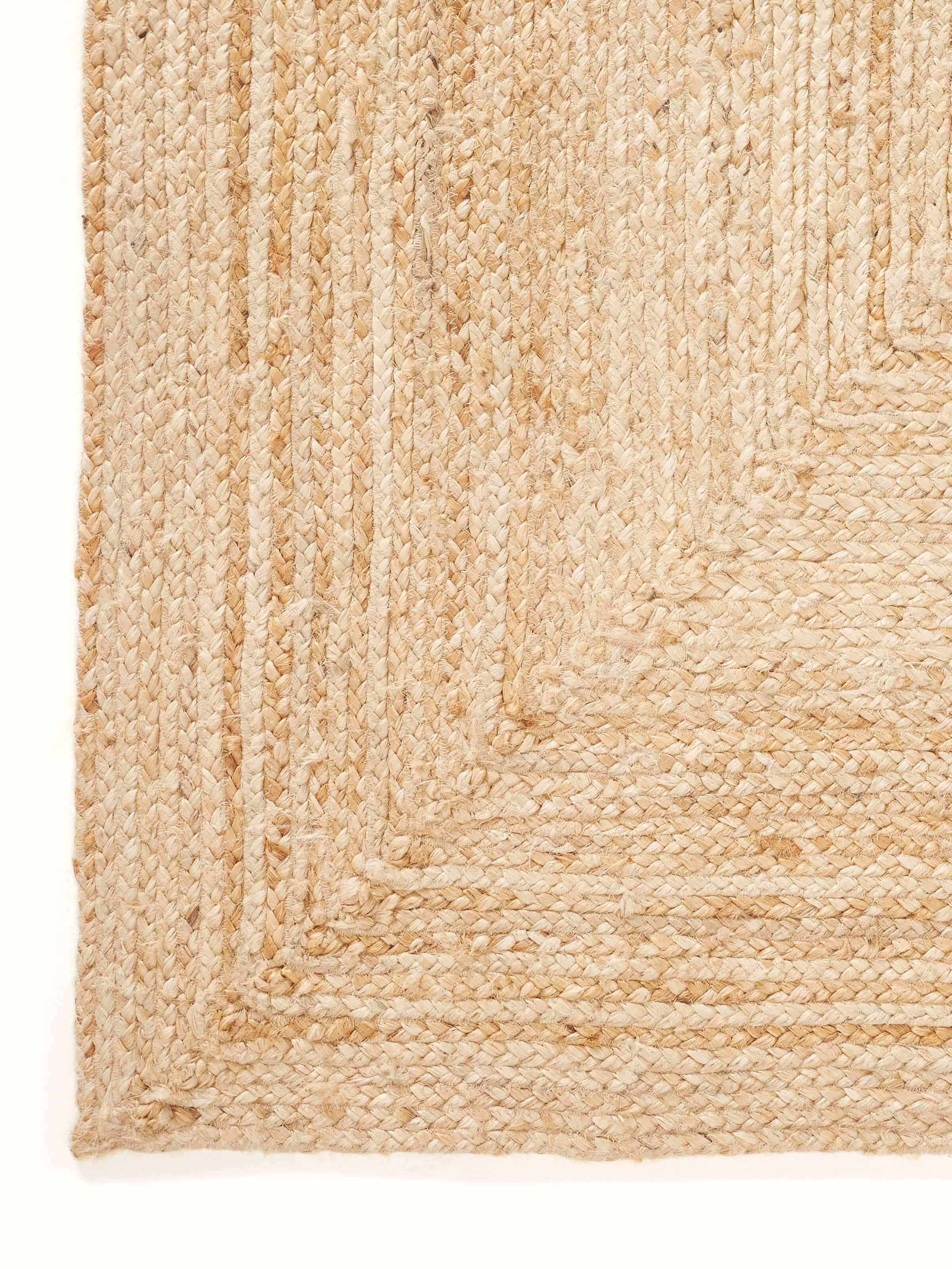 Detailed close-up of the concentric braid pattern on the beige Lawan jute rug, showcasing its high-quality natural fiber construction