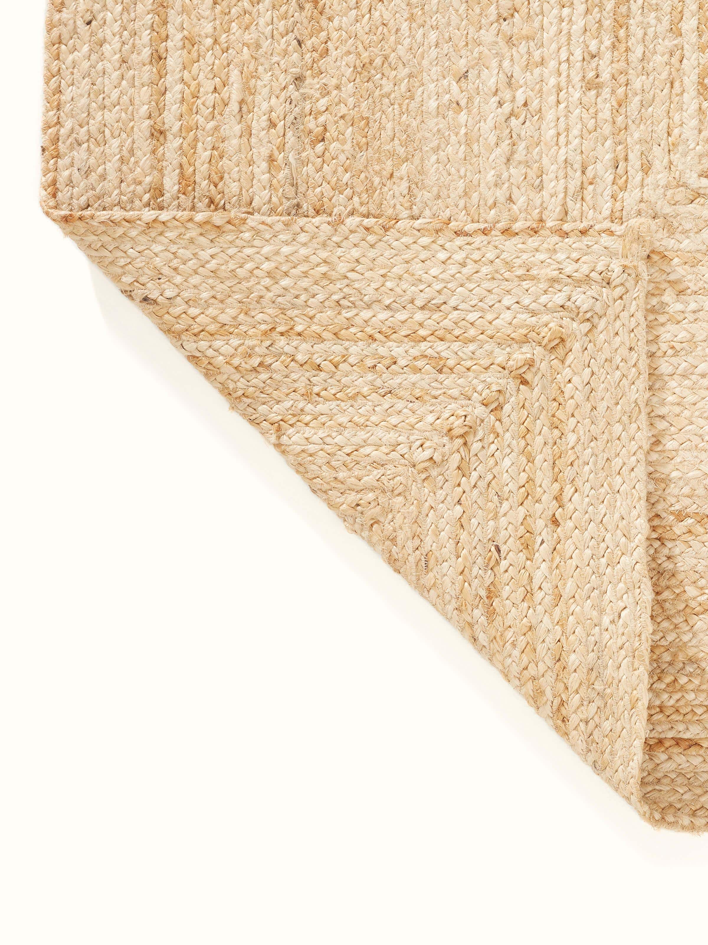 Full view of the braided concentric rectangle beige Lawan jute rug (4x6 ft), placed on the floor to show its size and design integration in a room
