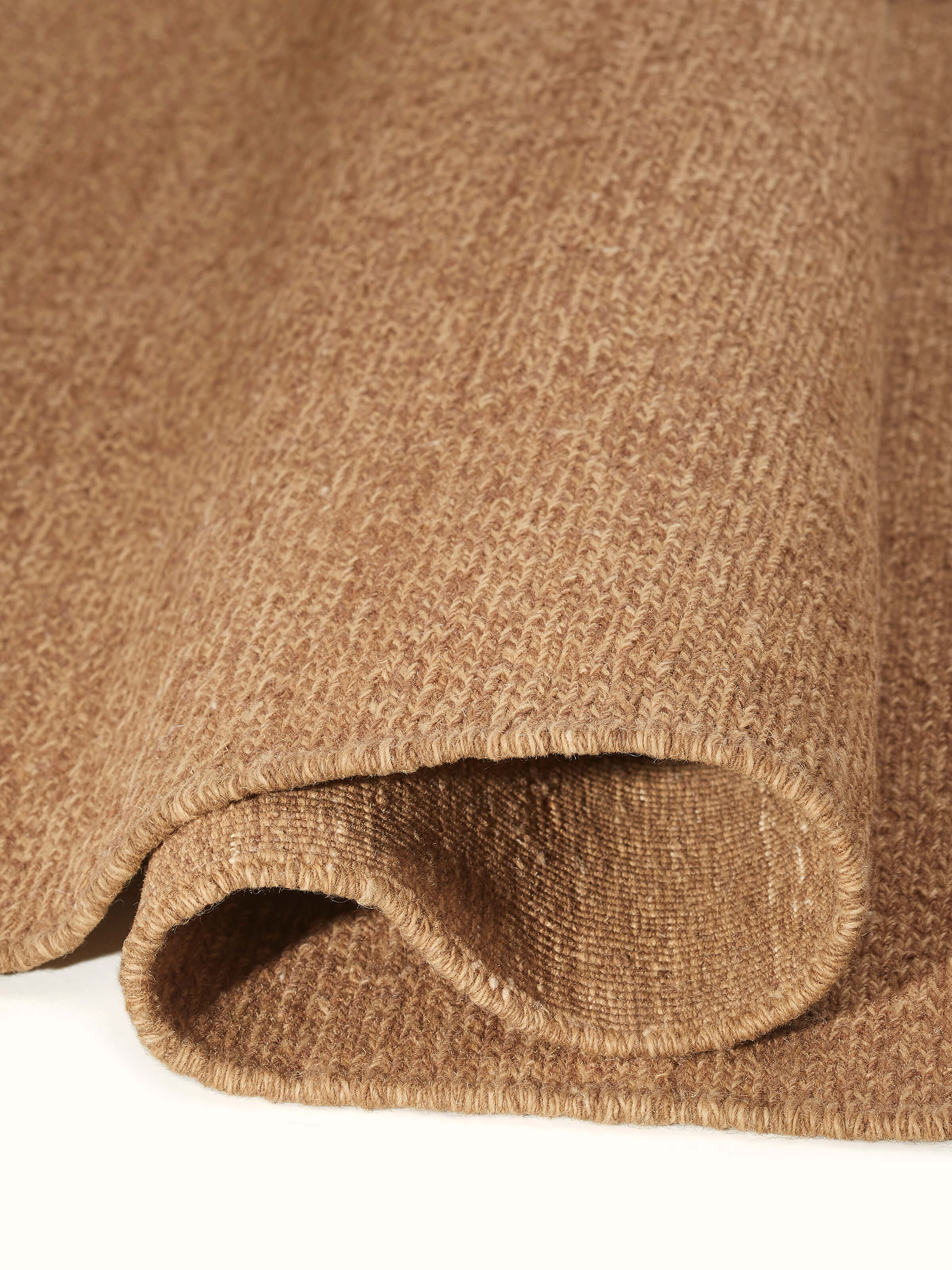 Detailed view of the hand-knotted edges of the brown wool rug, emphasizing the artisanal quality.