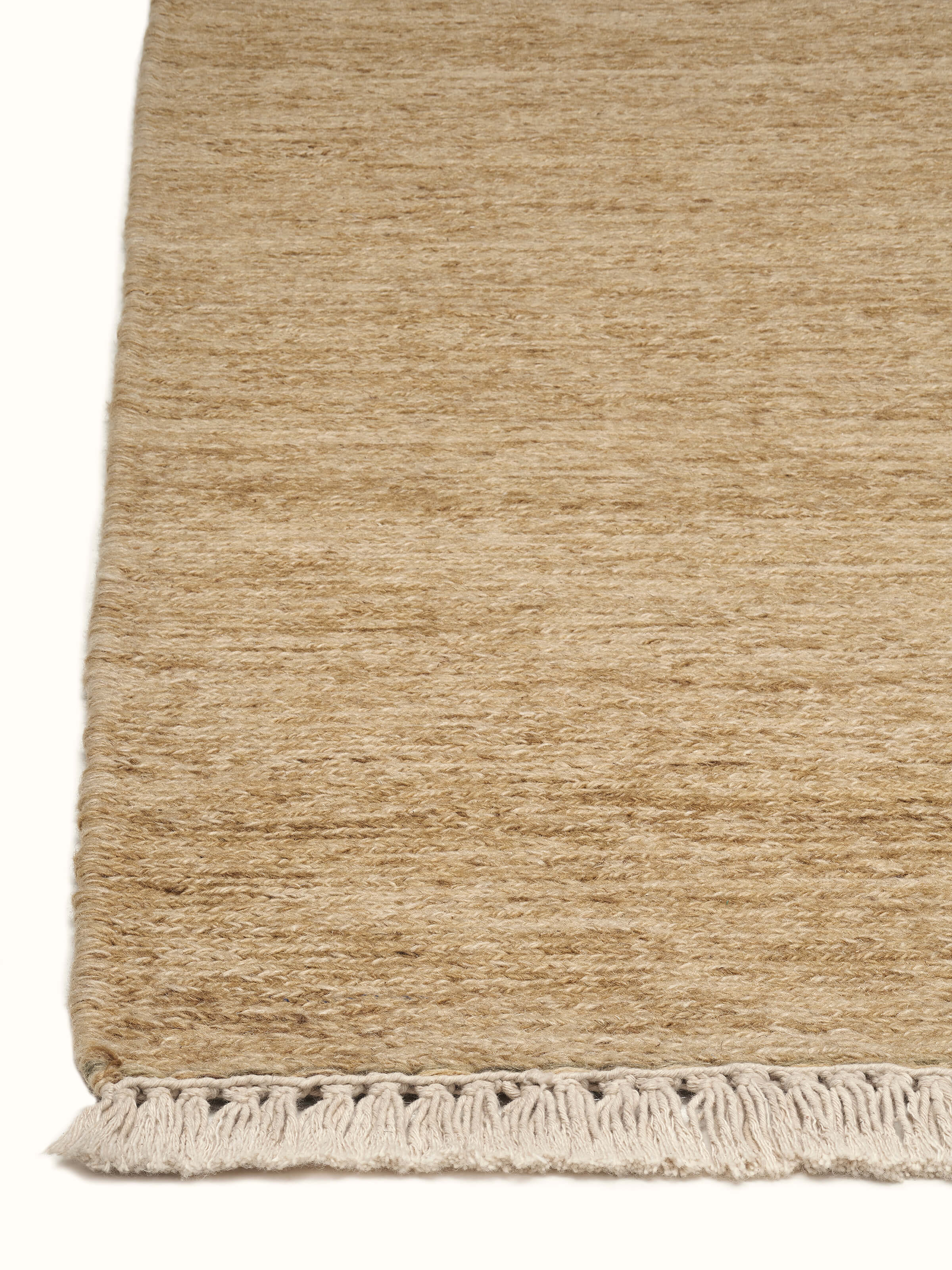 Solid textured Sumak beige Bhadohi wool hand-knotted rug, displayed in a room setting to show its practical use