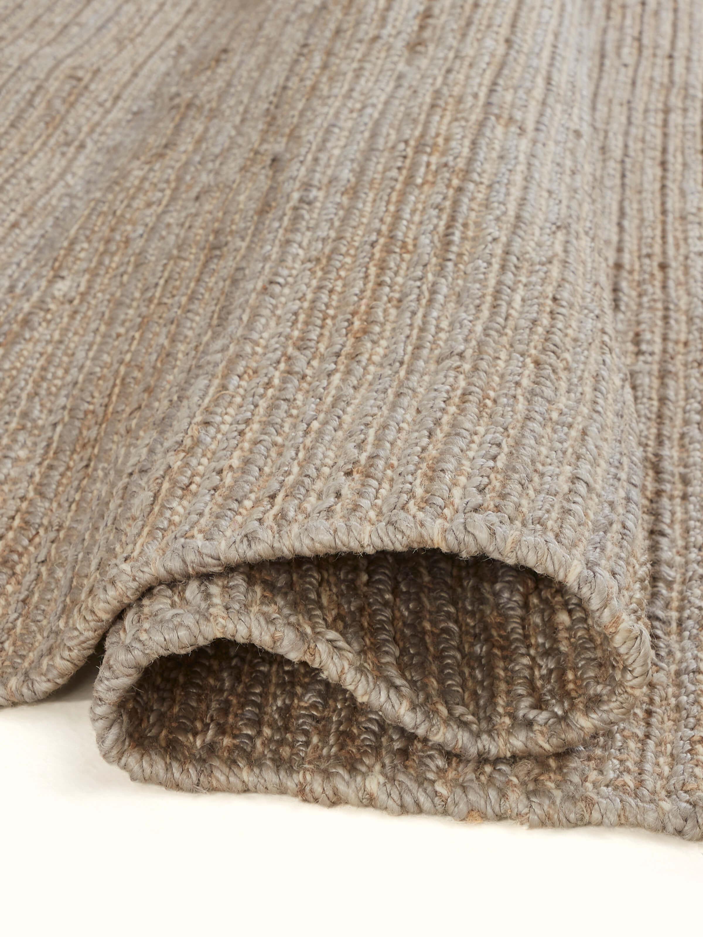 Side view of the Textured Solid Grey Jute & Wool Rug, emphasizing its thickness and edge details.