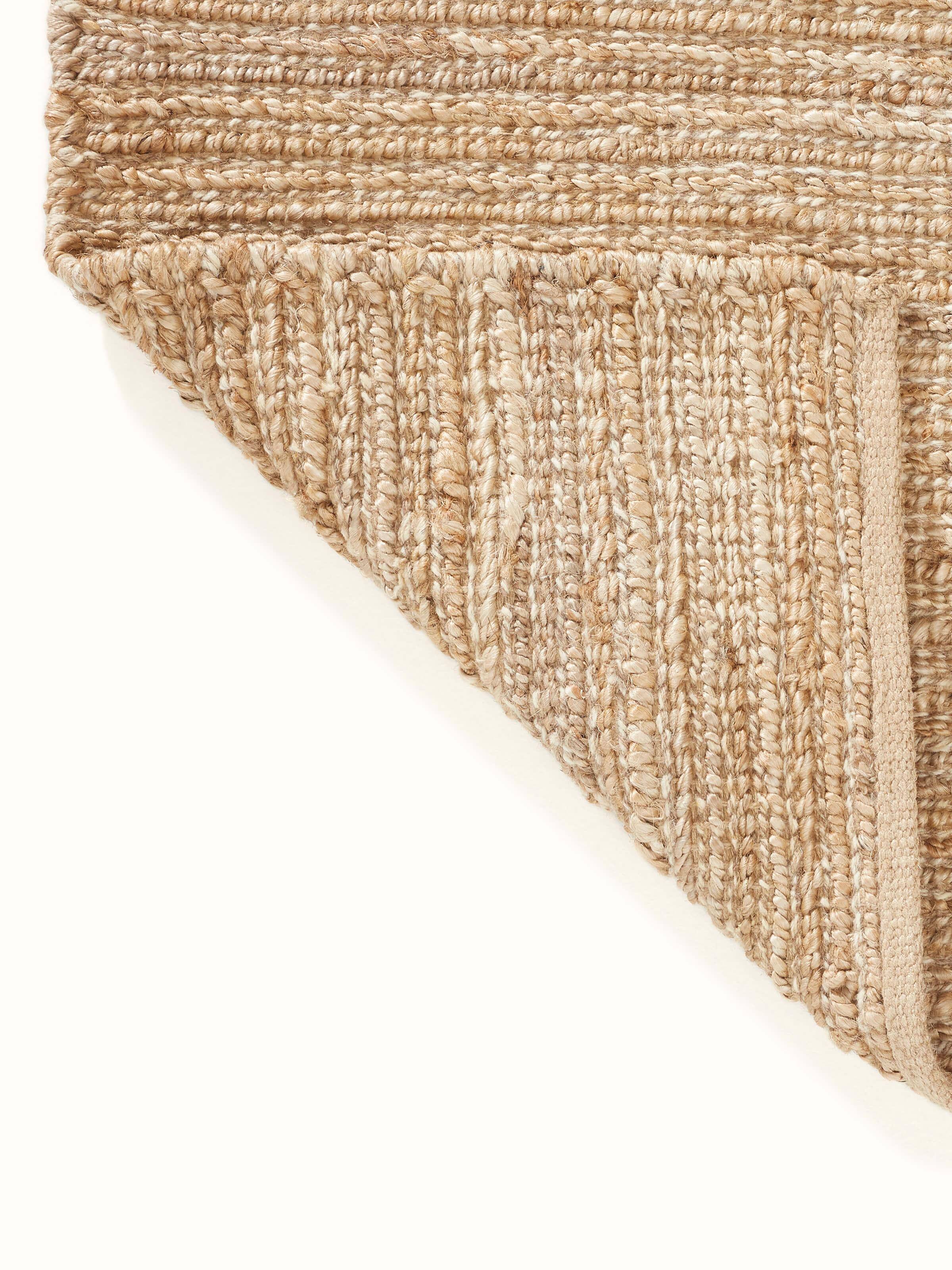 Full view of textured solid beige jute & wool natural fibre rug (5x8 ft) laid out, displaying its color and texture in a room setting.