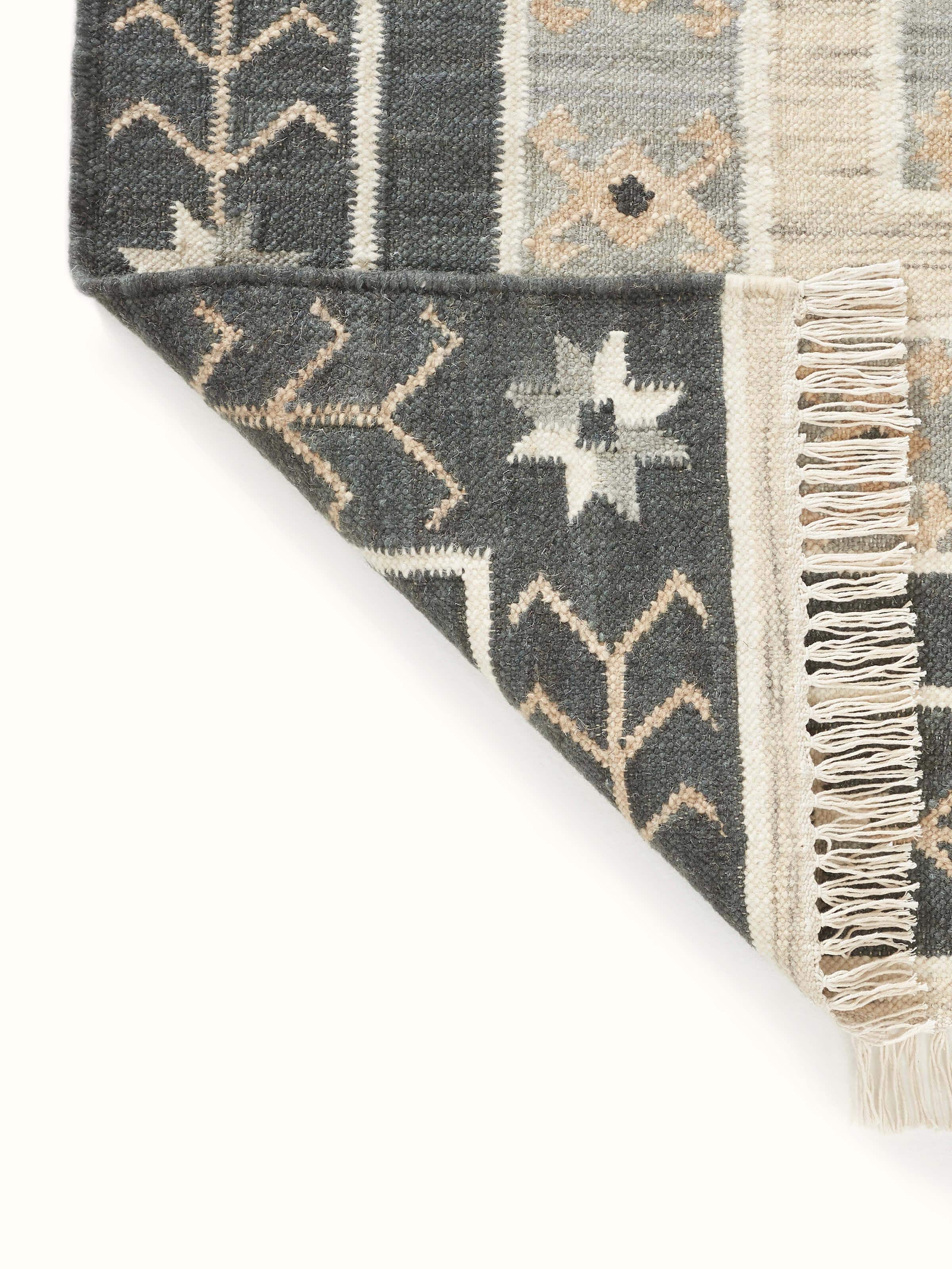 Folded Contemporary geo grey wool panja dhurrie displaying its wool texture and design in a compact form.