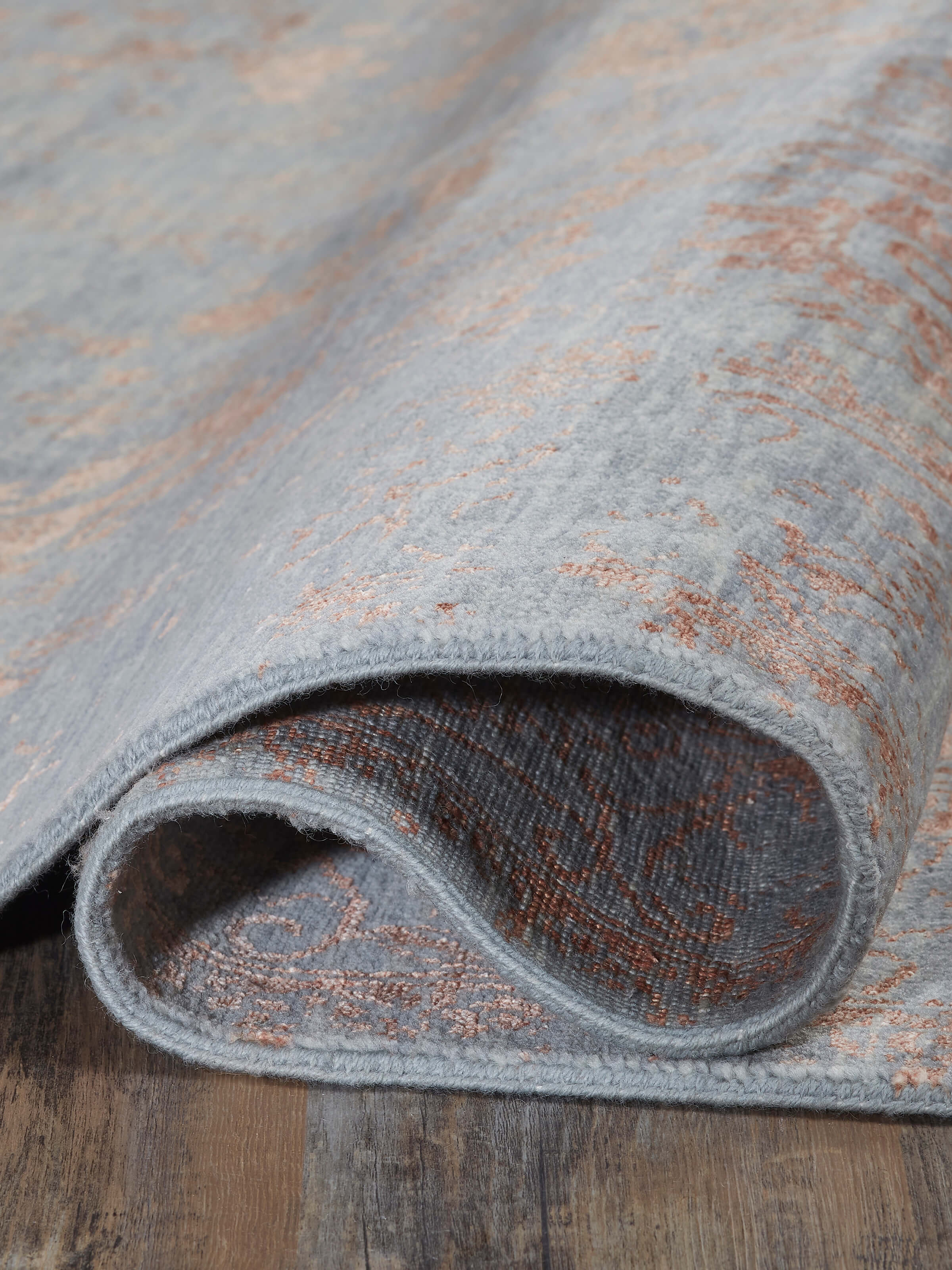 Side view of the Distressed transitional dark grey copper Agra rug showing its thickness and edge detailing