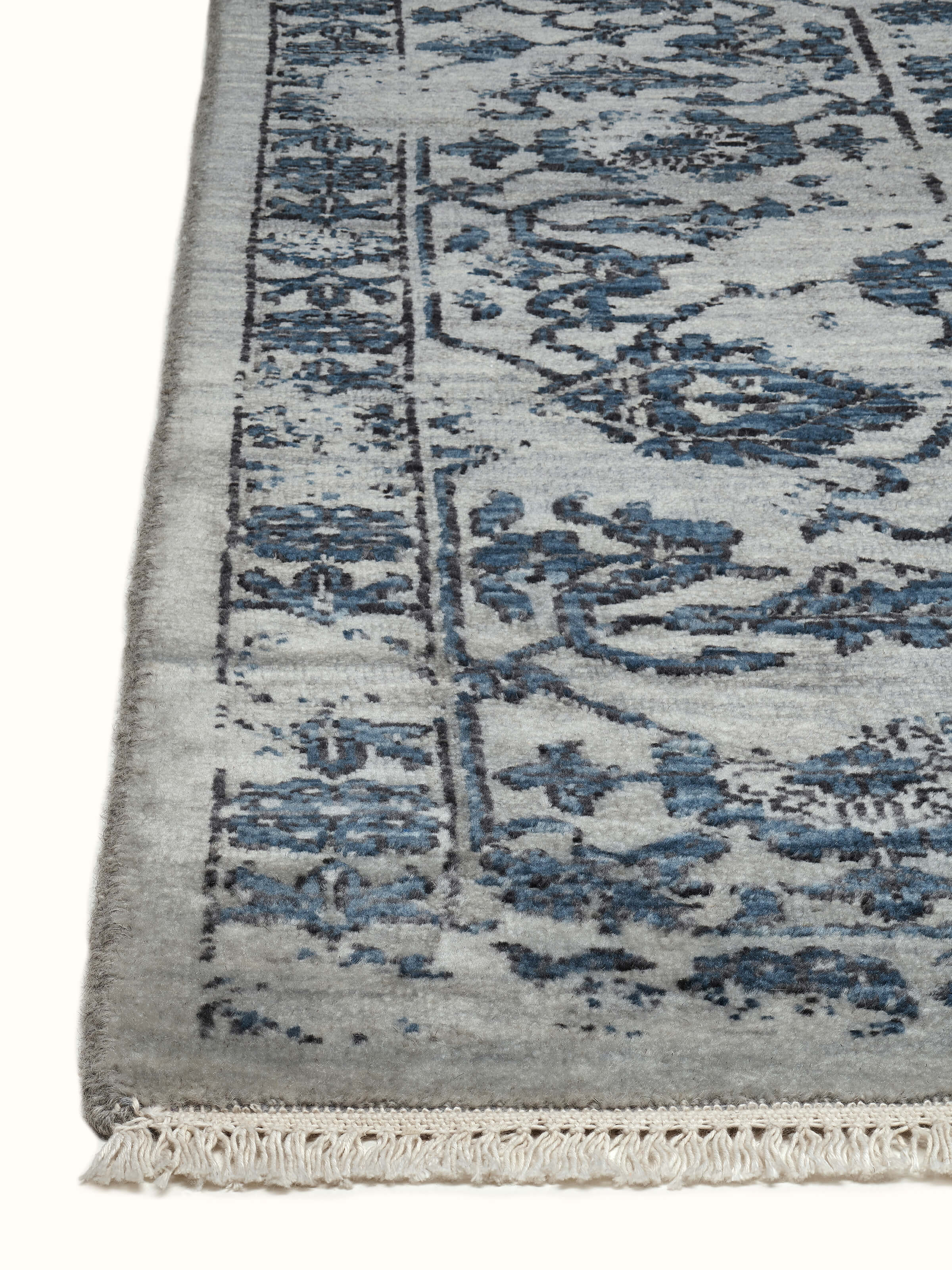 Angled top view of Swadesh Distressed Transitional Agra Wool Rug in grey and blue tones, hand-knotted with traditional artistry.