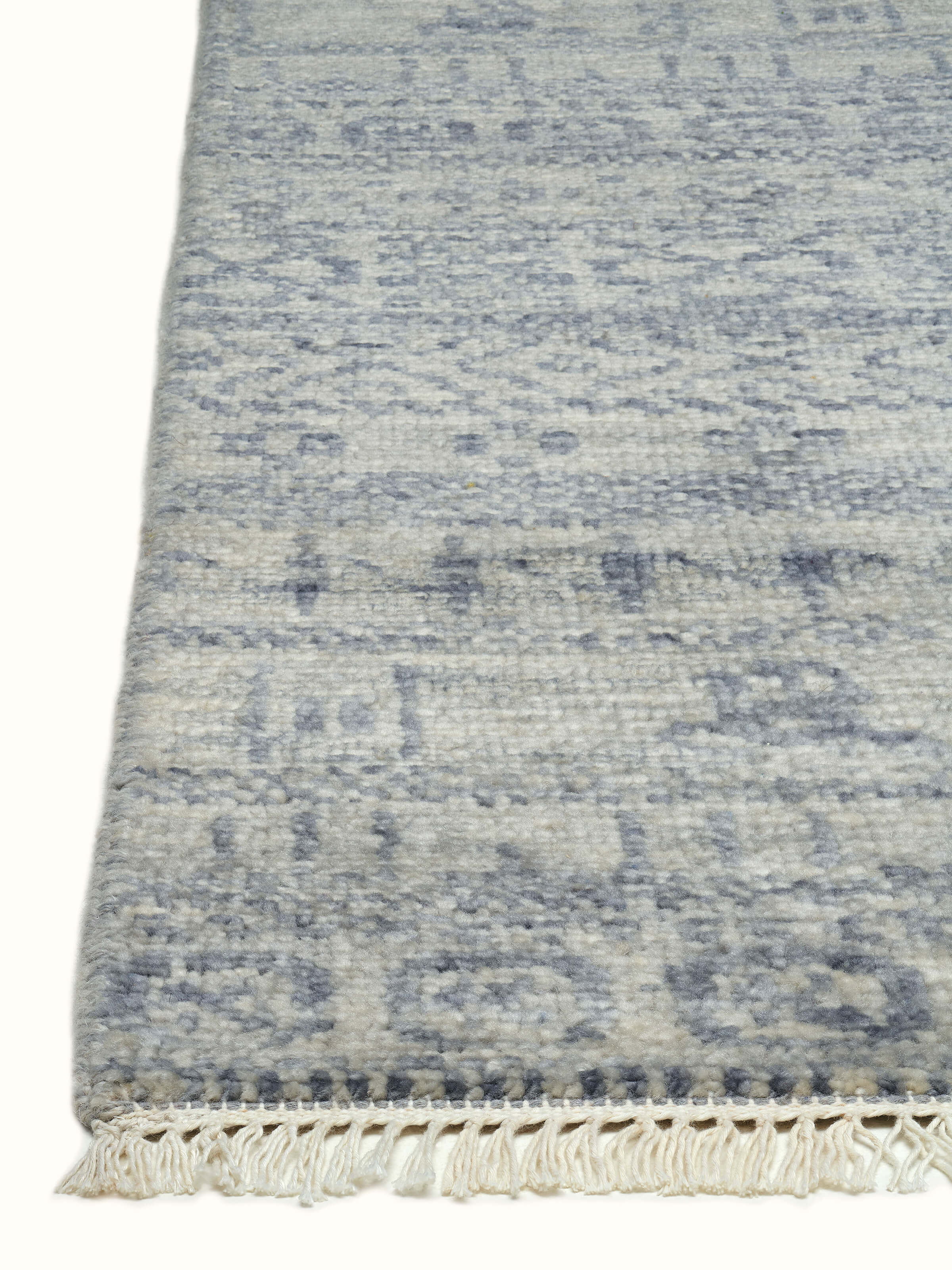 Angled view of the grey-blue Agra wool rug, demonstrating the texture and craftsmanship of the hand-knotted design.