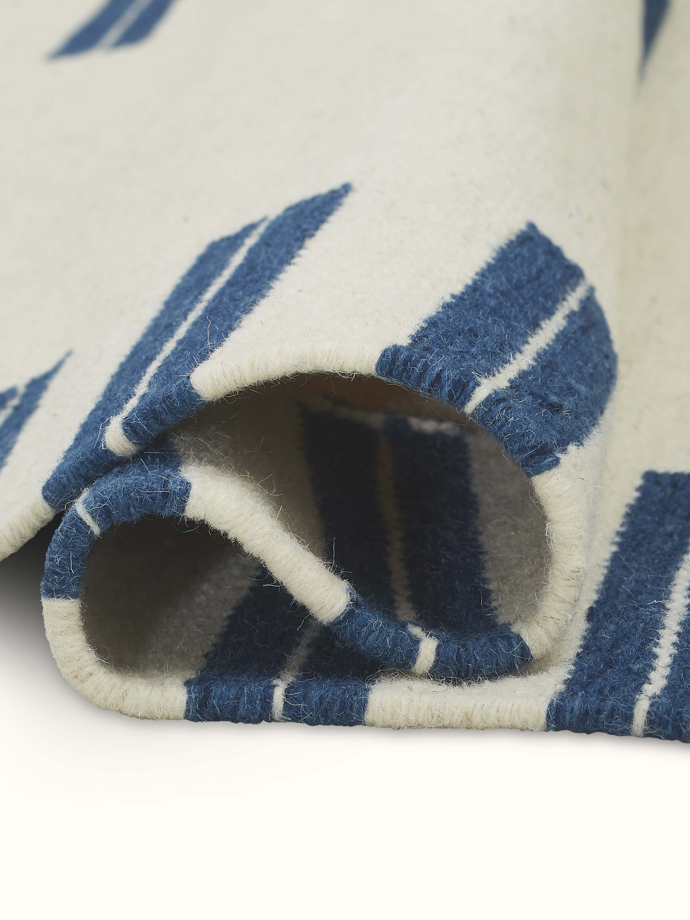 Side view of Geo Border Ivory Blue Gujarat Wool & Cotton Panja Dhurrie, showing its thickness and edge details.