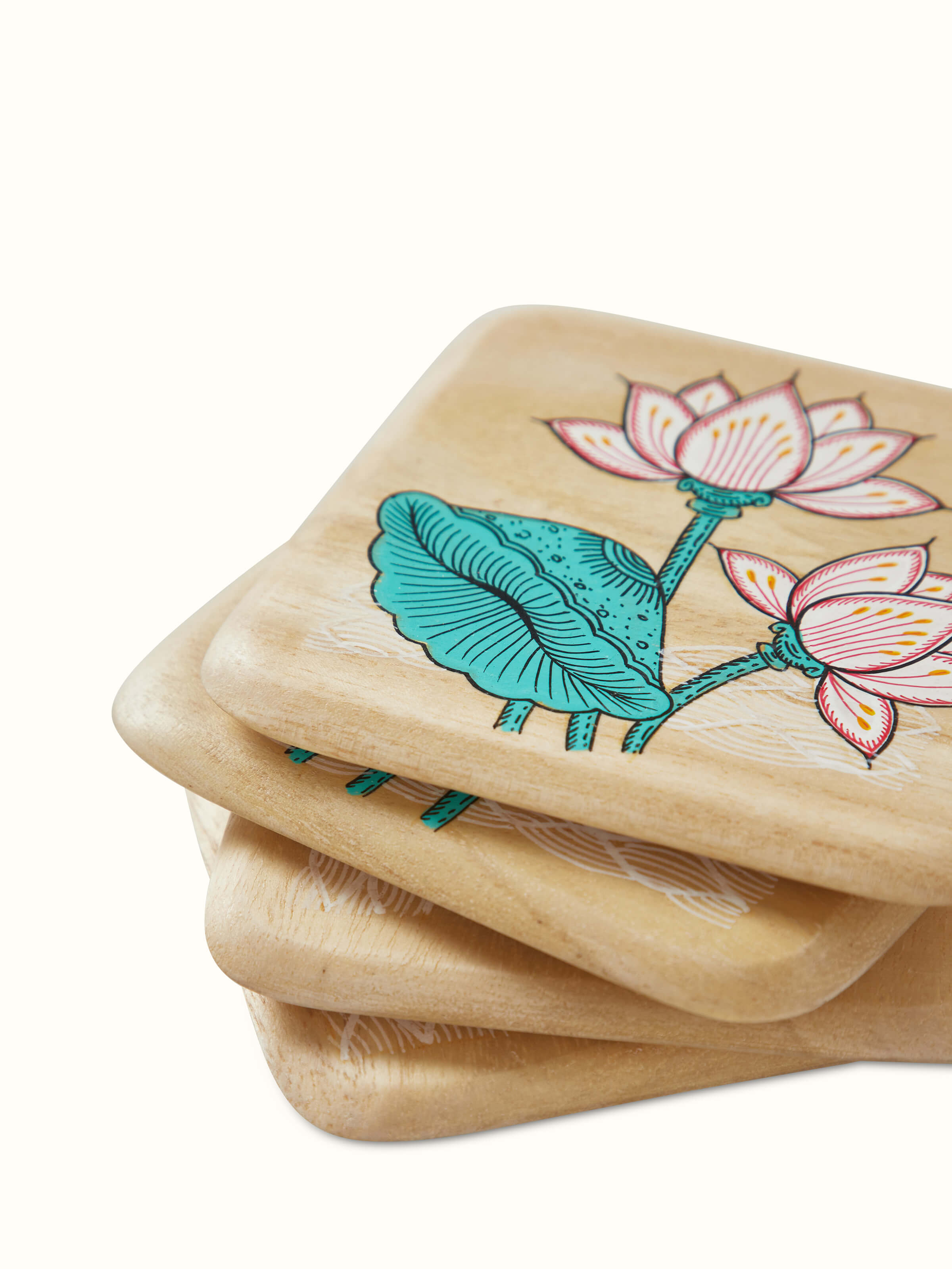 Detailed view of the carved gamhar wood coasters in white and teal, highlighting their craftsmanship and design.