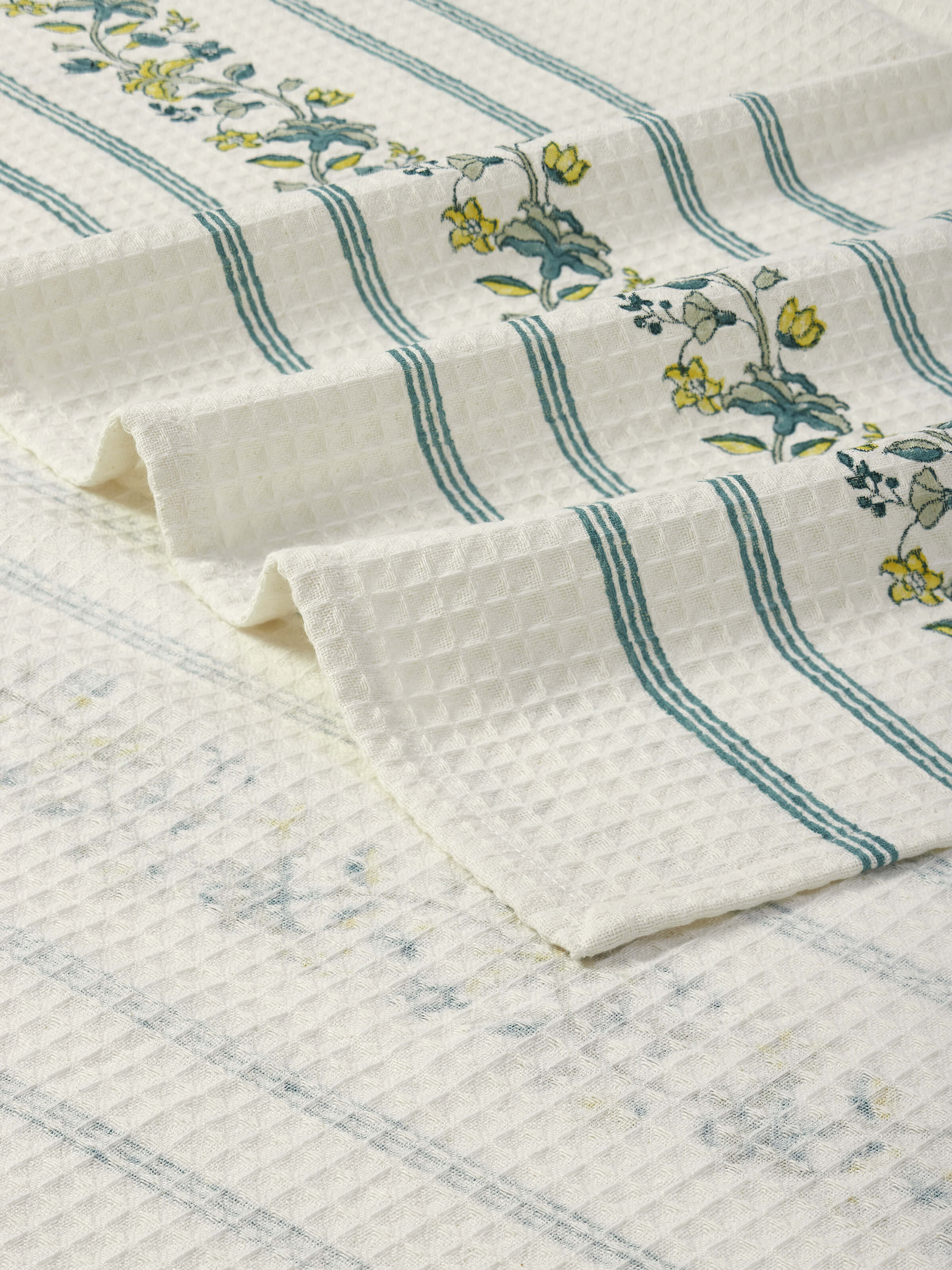 Perspective view of Palampore stripe yellow floral cotton Sanganeri block printed bath towel (XL) emphasizing its large size and design.