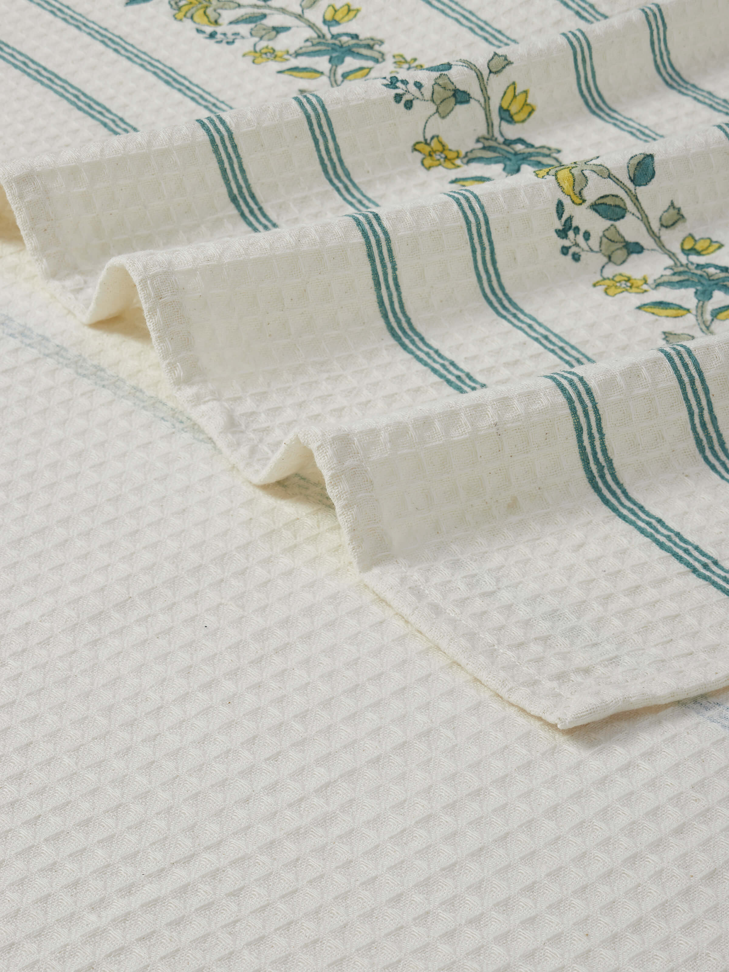 Angled view of Palampore stripe yellow floral cotton Sanganeri block printed bath towel (L) displaying its full design.