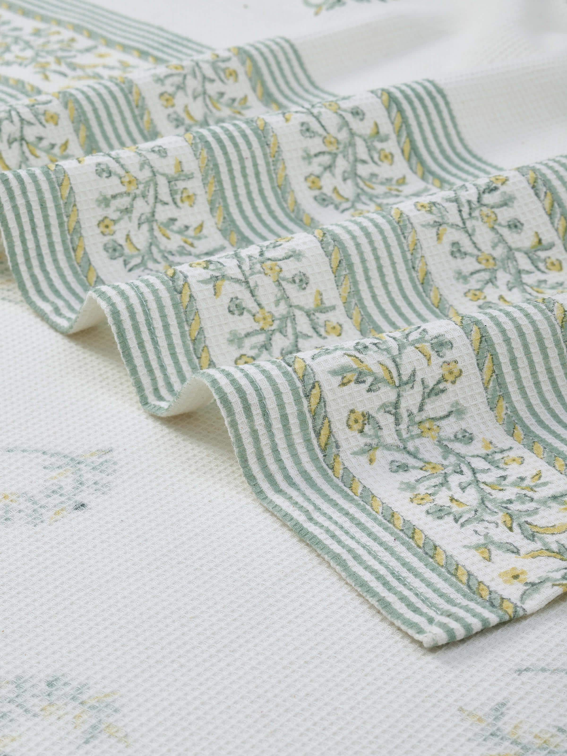 Perspective view of Ambi allover yellow floral cotton Sanganeri block printed bath towel (L) displaying its full print and size.