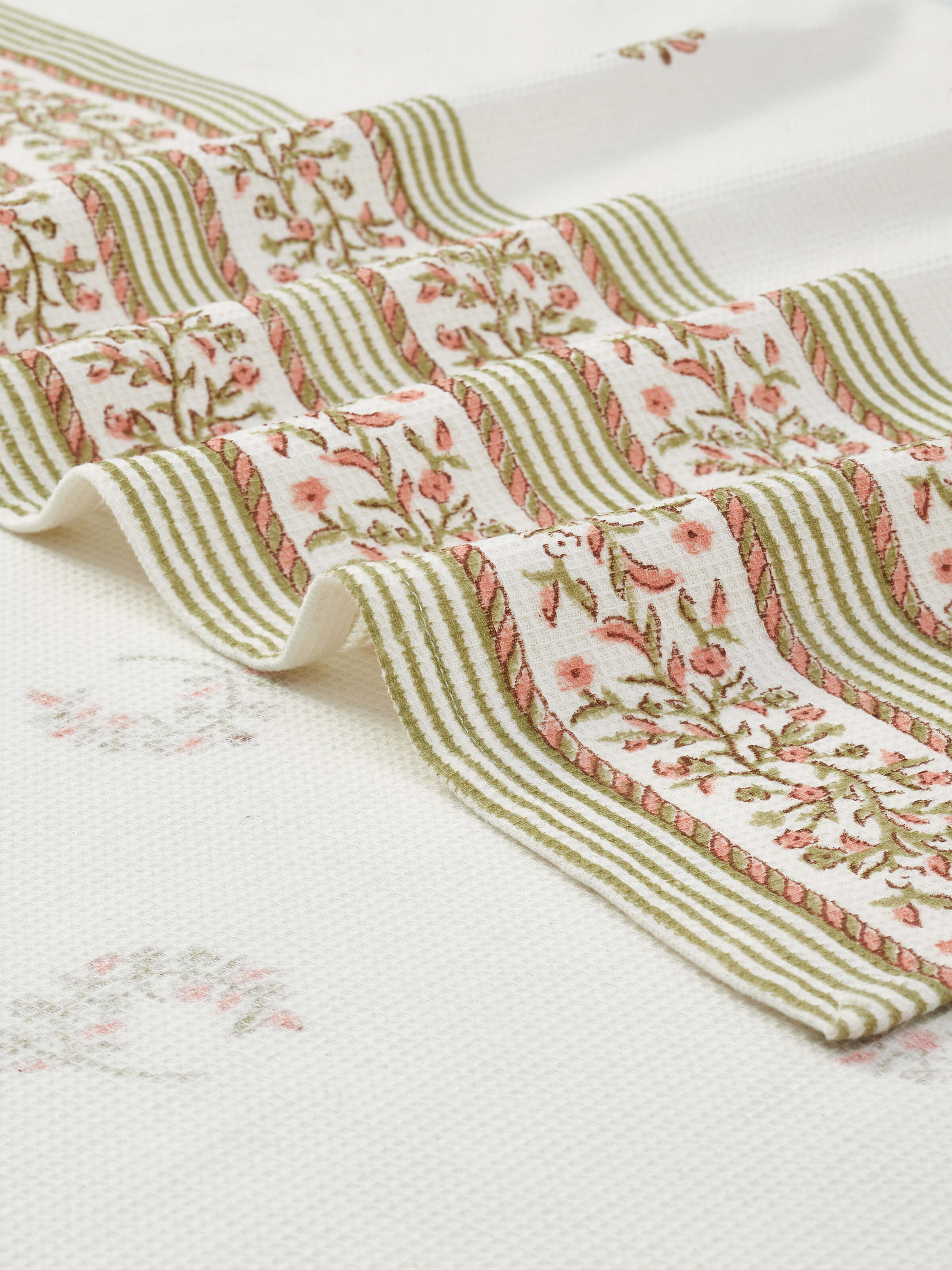Detailed view of Ambi allover peach floral cotton Sanganeri block printed bath towel (L), showcasing the softness and fabric quality.