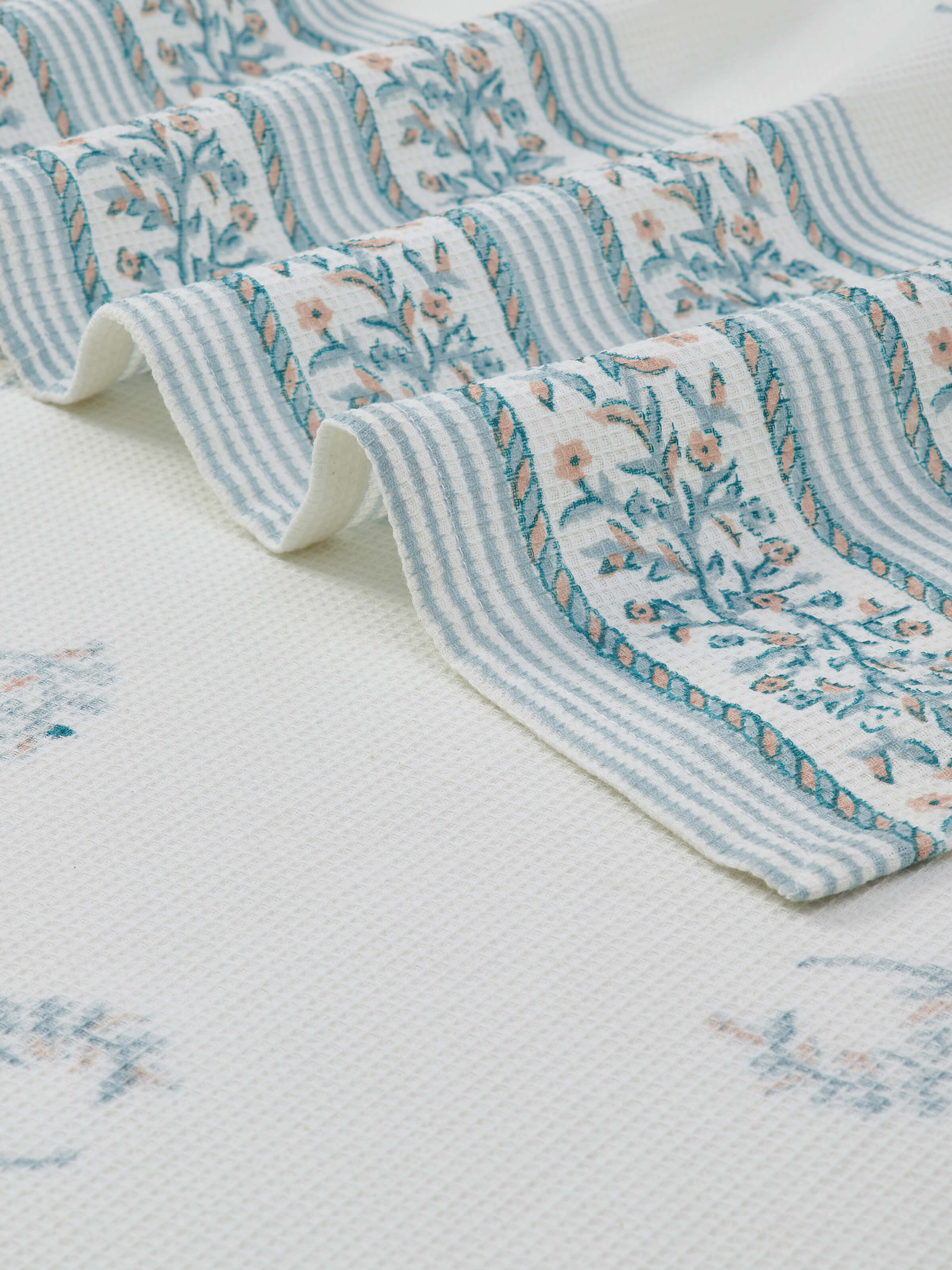 Detailed view of Ambi allover blue floral cotton Sanganeri block printed bath towel (L) highlighting the block print and fabric texture.