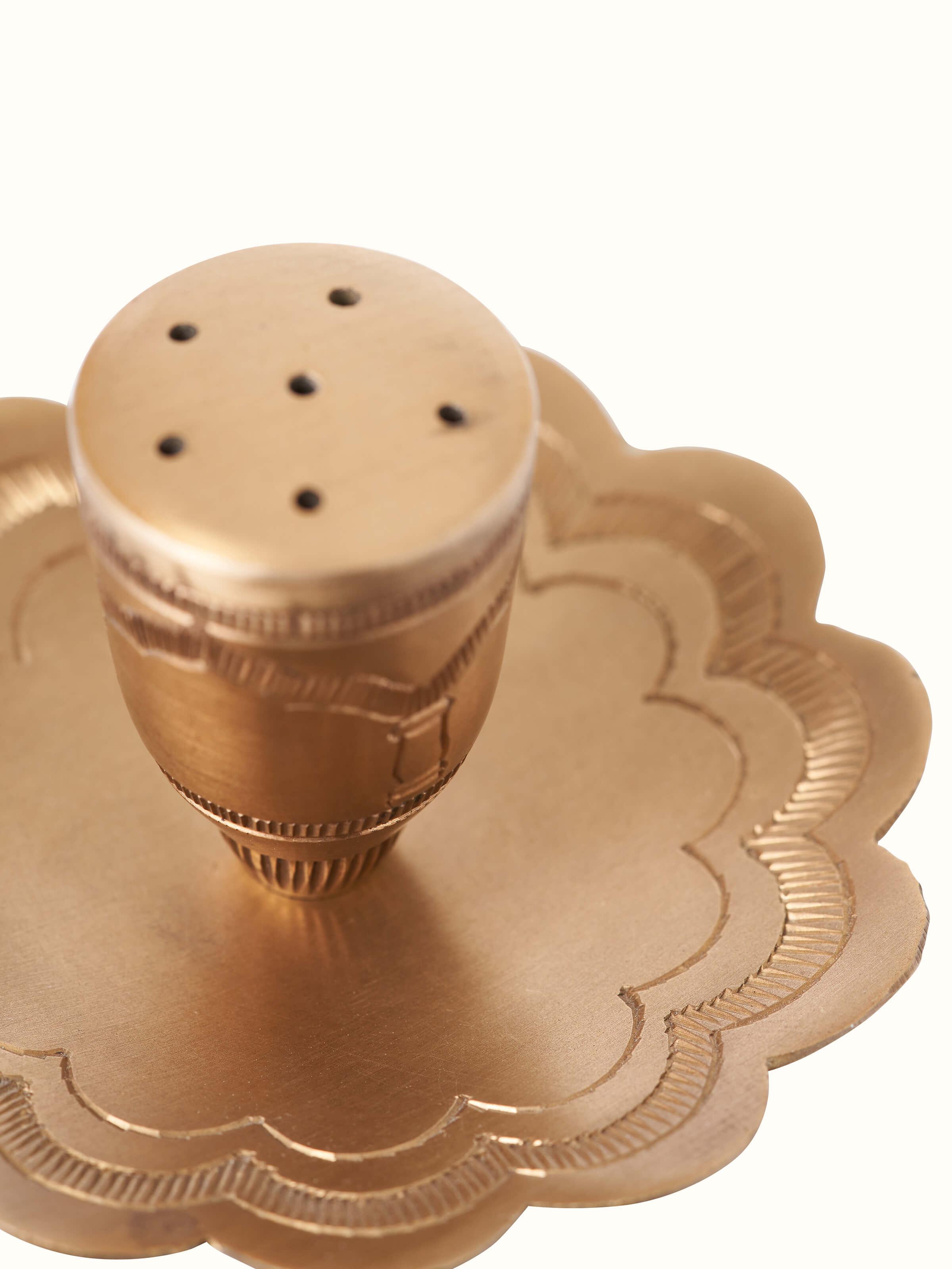 Top view of polished brass incense stick holder showing the central placement and design for holding incense sticks