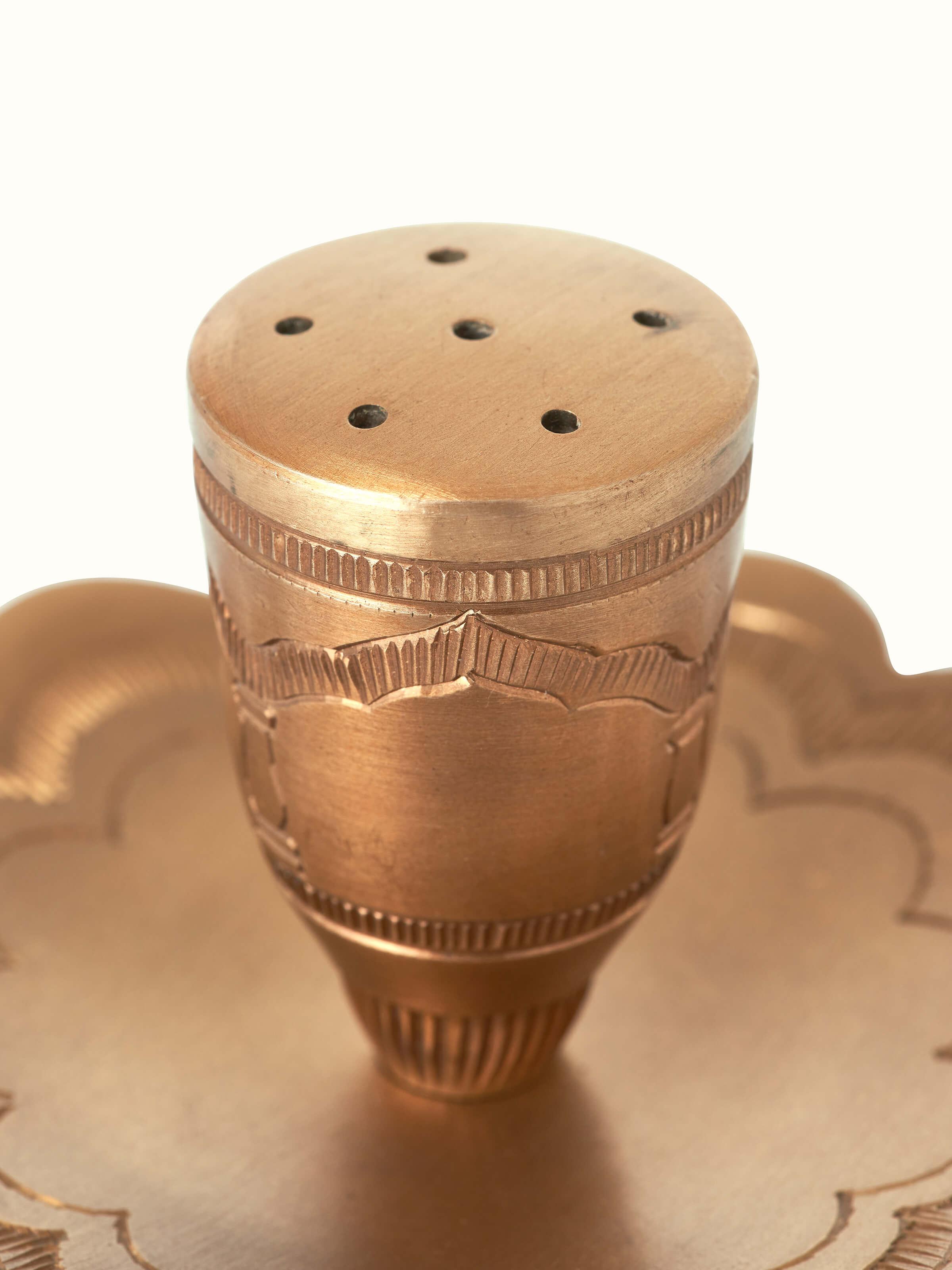 Close-up of polished brass incense stick holder focusing on the intricate details and craftsmanship of the brasswork