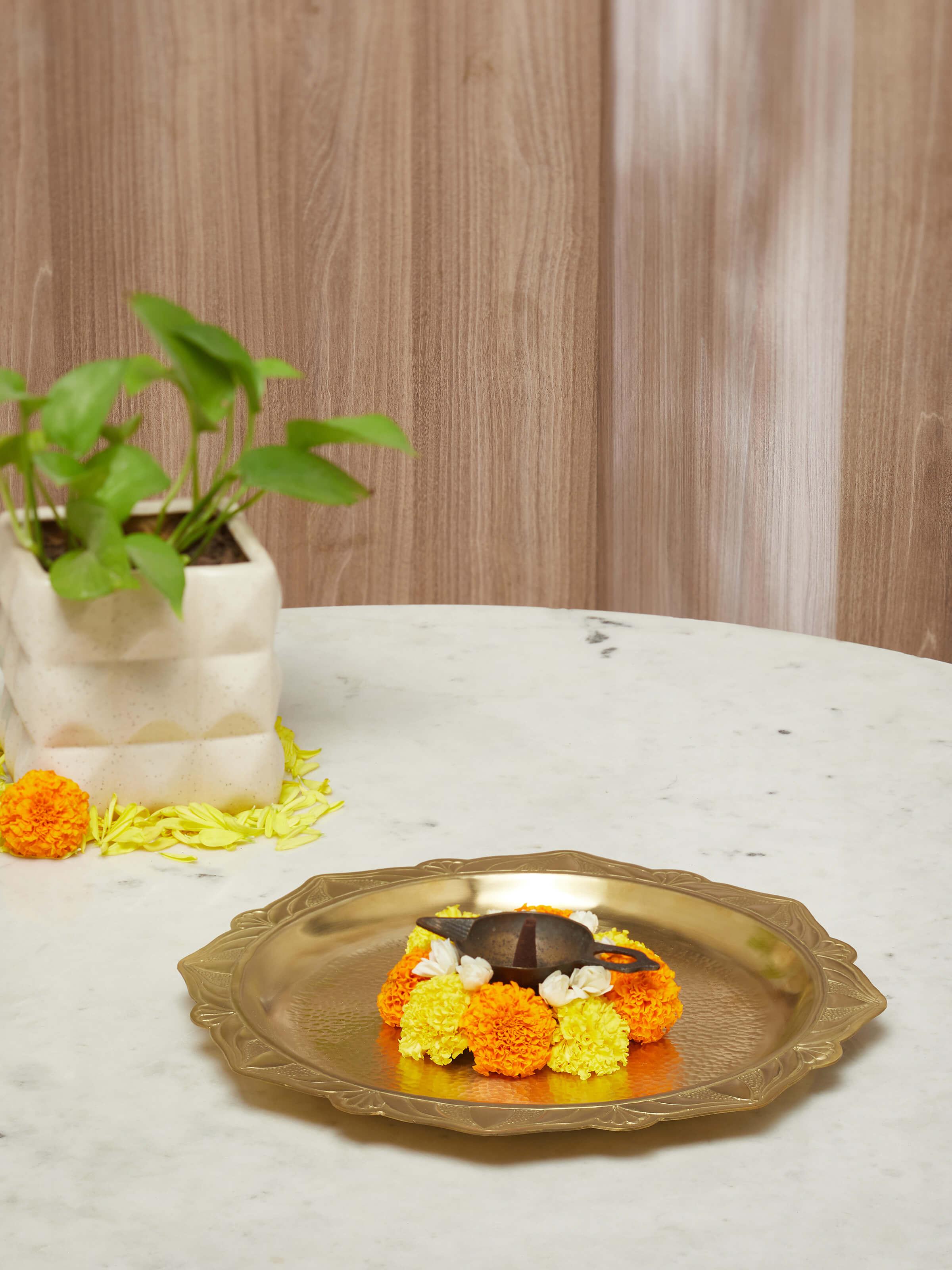 Side view of polished brass ajradha pooja thali, highlighting intricate designs