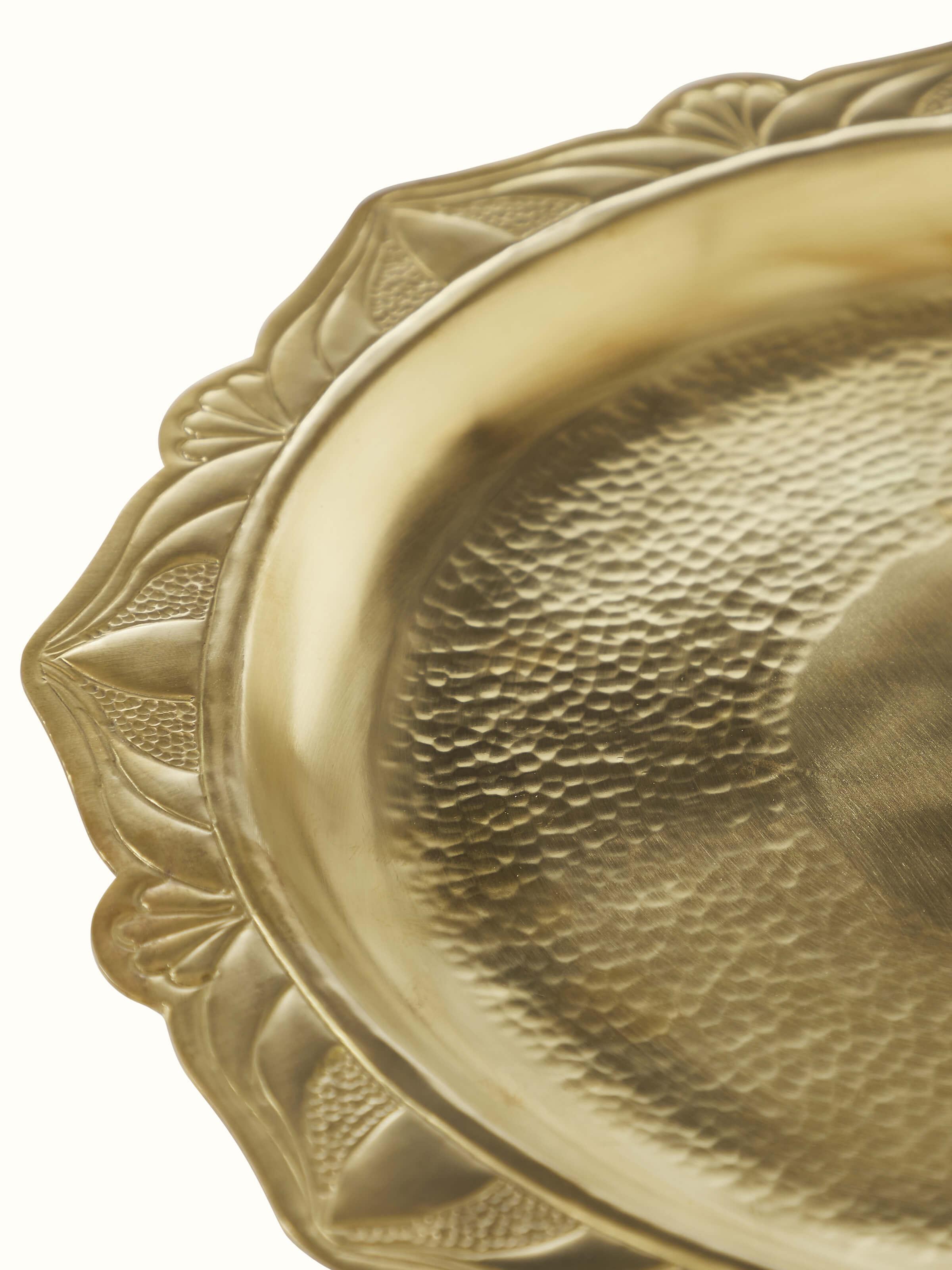 Close-up view of polished brass ajradha pooja thali, emphasizing detailed carvings
