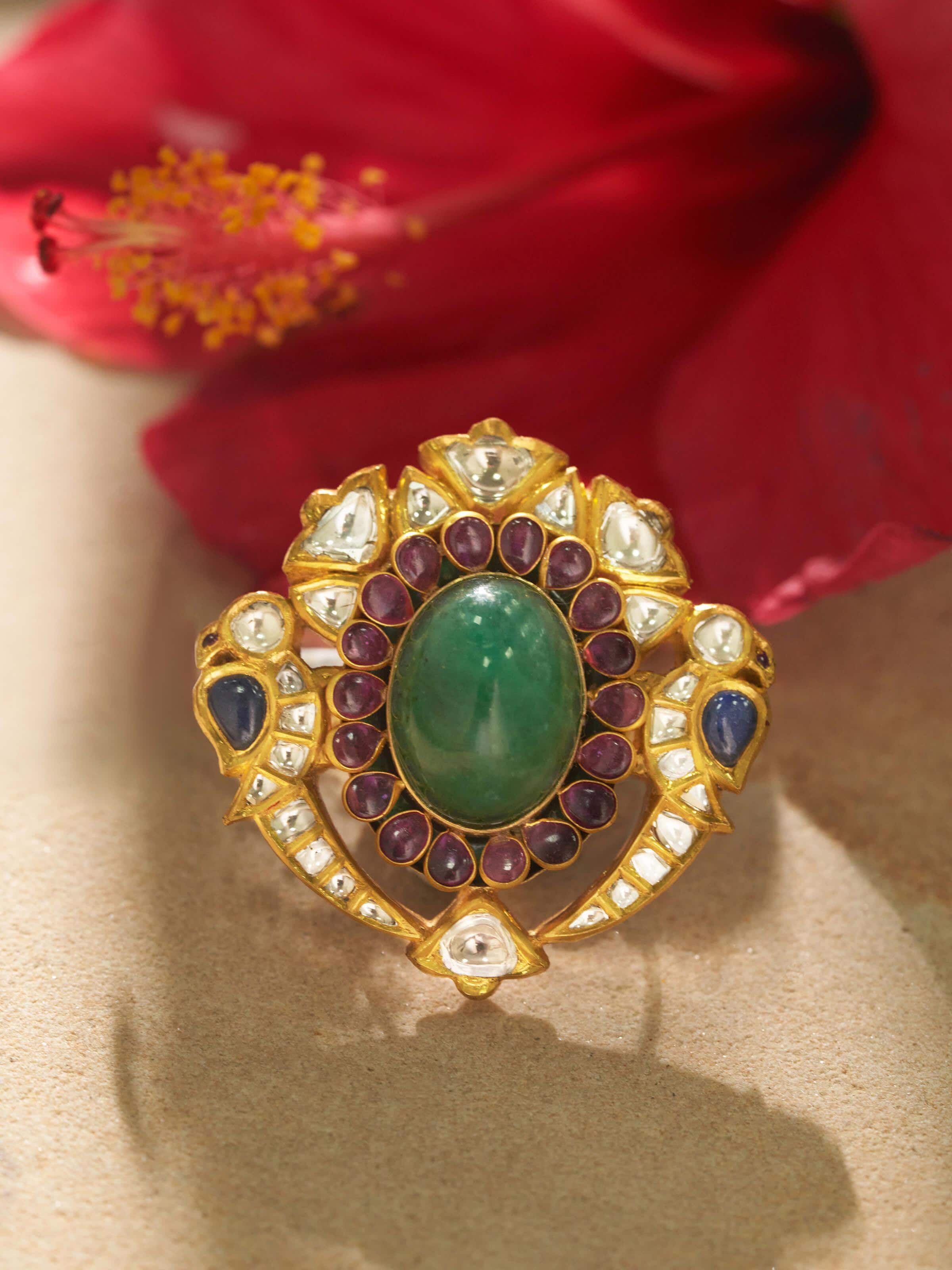 Detail shot of gold ring showing enamel work and gemstone cluster
