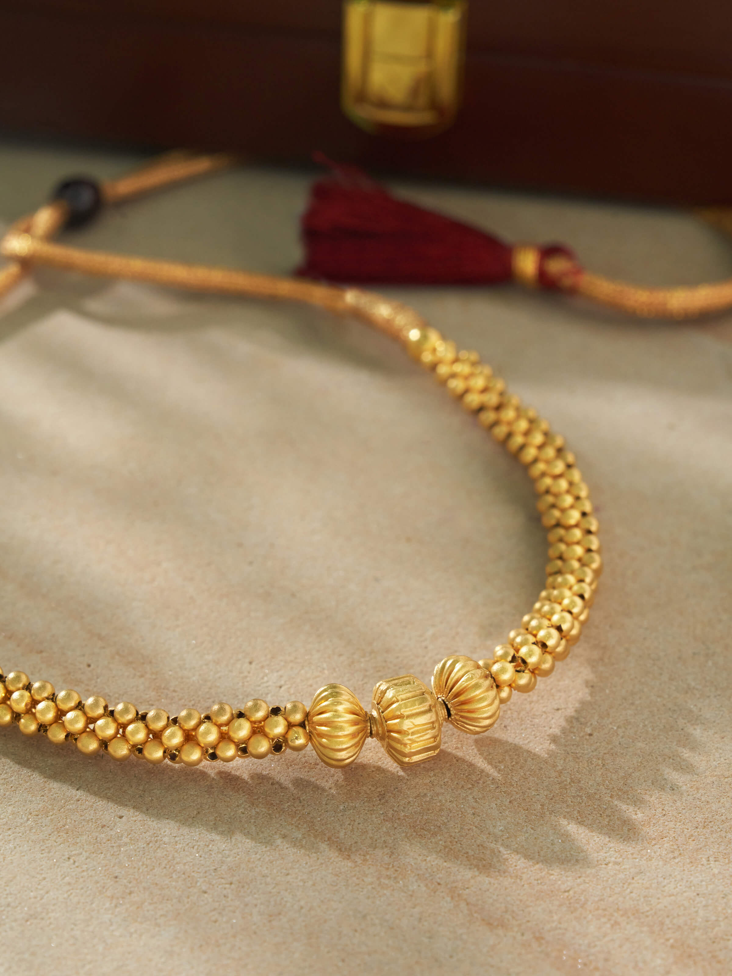 Angled view of Thushi 22 Karat gold necklace capturing depth of design and traditional detailing.