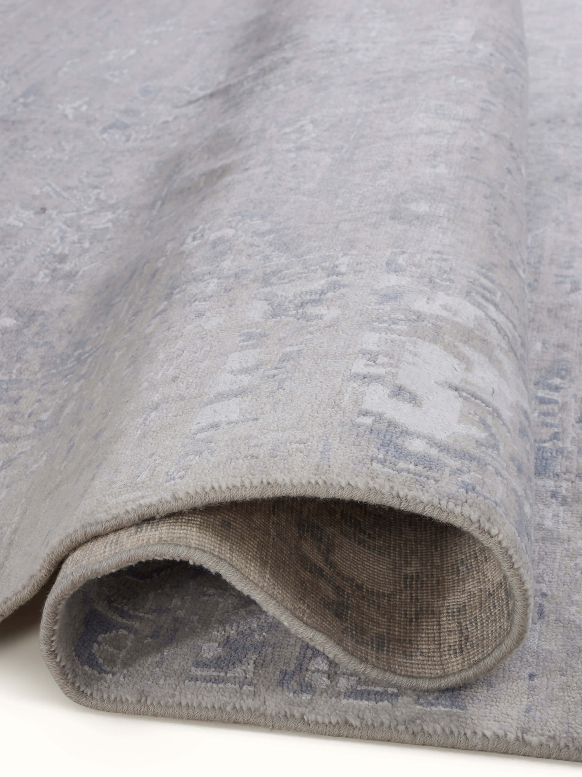 Artistic view of distressed transitional grey blue Bhadohi wool and silk hand-knotted rug in a room setting