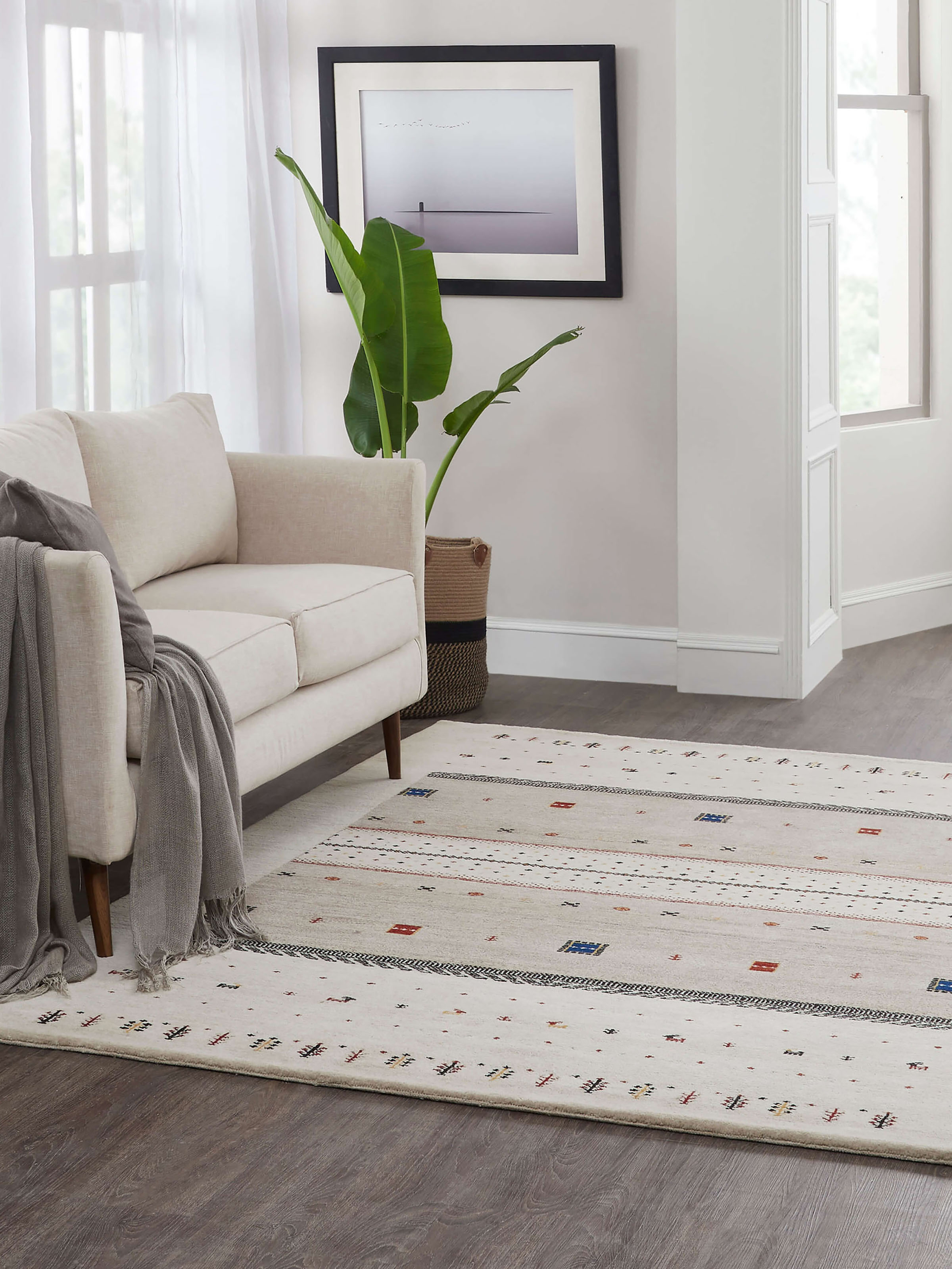 Lifestyle shot of ivory-beige Gabbeh Bhadohi wool rug with traditional hand-knotted design placed in a modern living room.